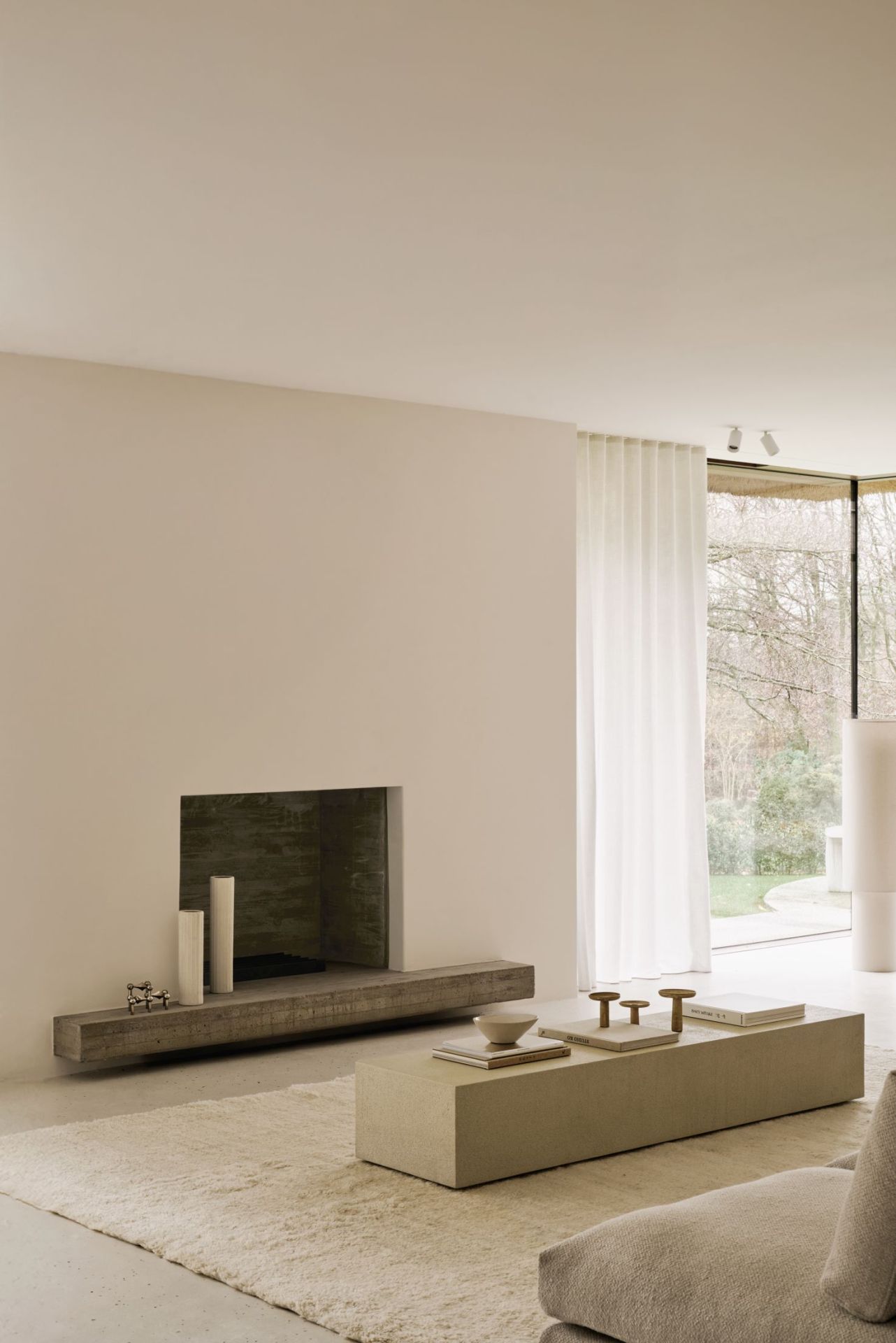 Wohnzimmer mit Ethnicraft Bodenregal, Kamin und Couch in minimalistischem Design.