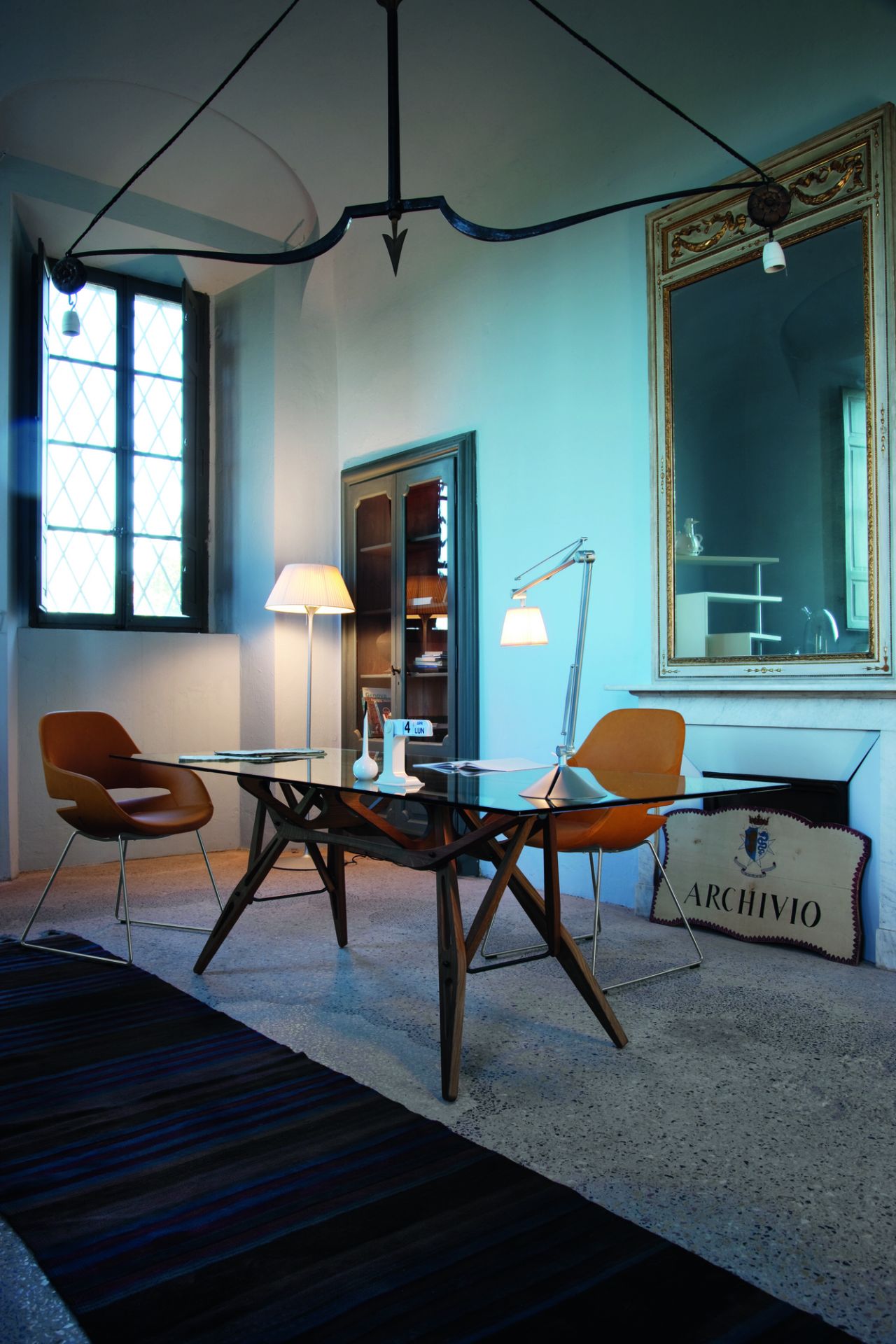 Innenaufnahme mit Zanotta Reale Tisch, Glasplatte, Holzgestell, Stühlen und Lampen.