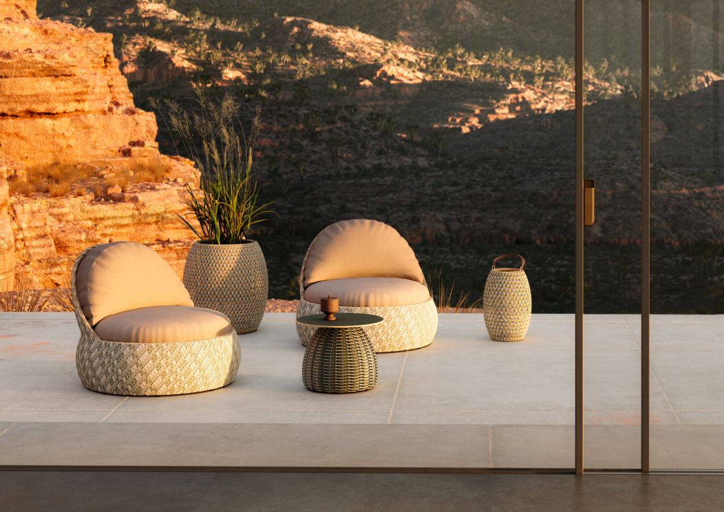 Dedon Porcini Beistelltisch, Ø61cm, aus geflochtenem Outdoor-Material, mit passenden Sesseln und Dekoration auf einer Terrasse.