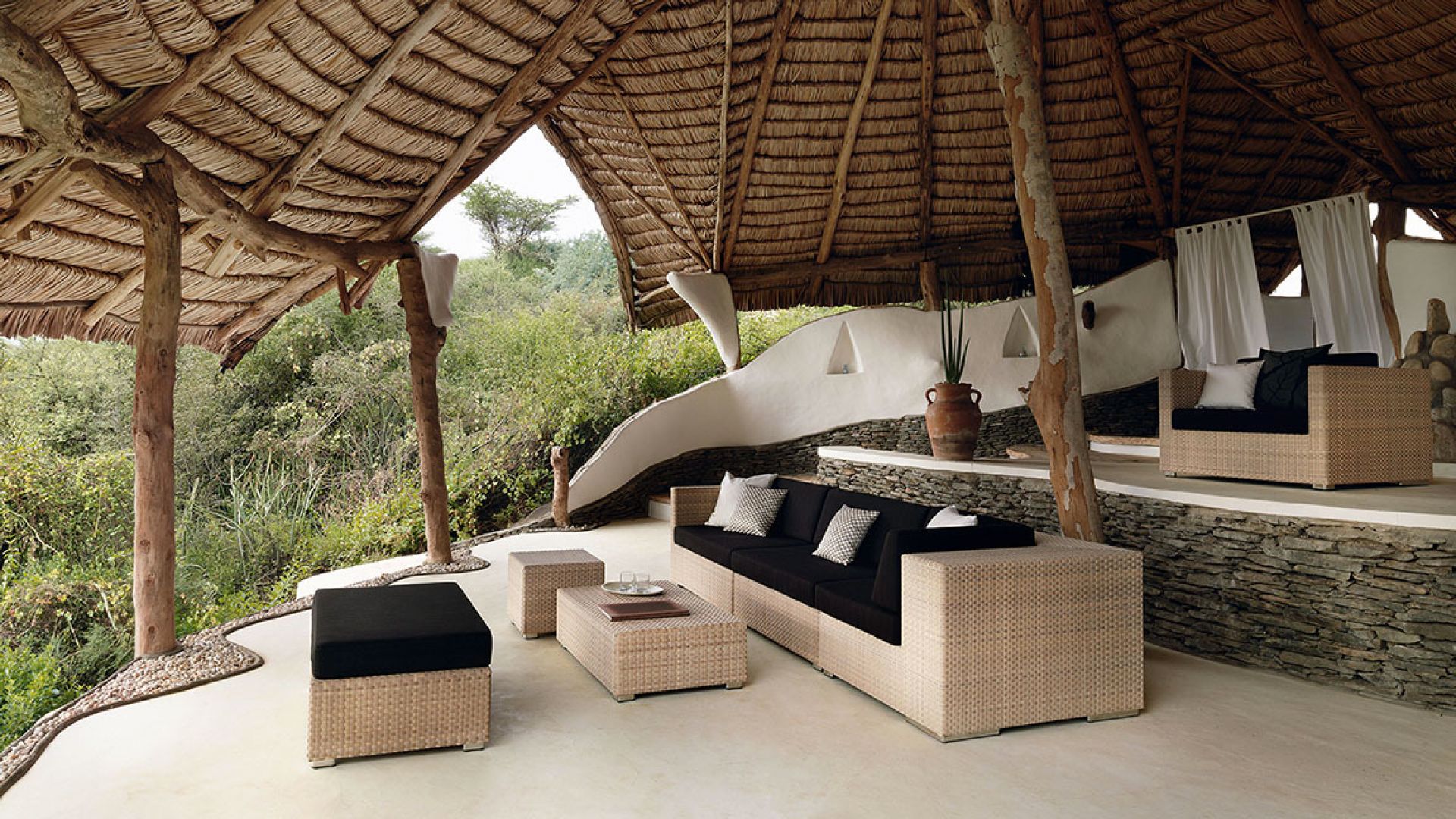 Dedon Lounge Modul rechts: Outdoor Lounge Möbel aus Rattan unter Strohdach.