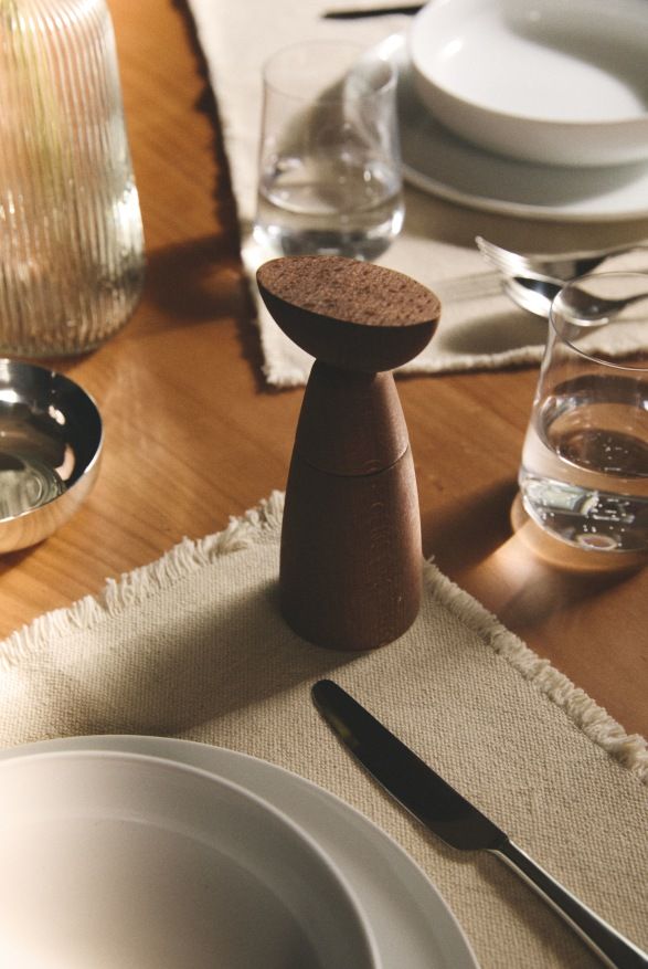 Oaxaca Salz- und Gewürzmühle von Alessi aus Holz auf einem gedeckten Tisch.