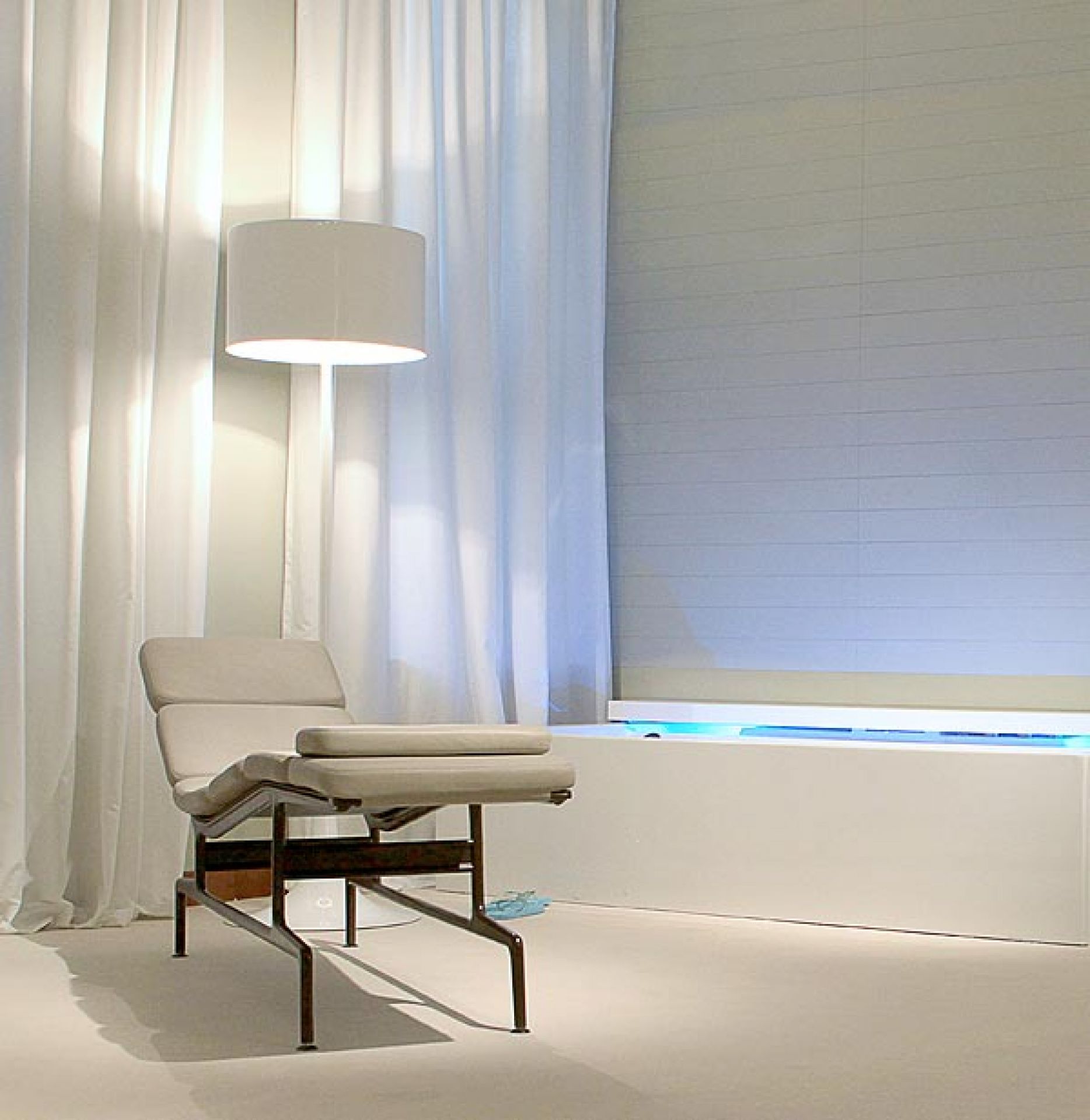 Weiße Spun Light Stehleuchte von Flos neben einem Sessel in minimalistischem Interieur.