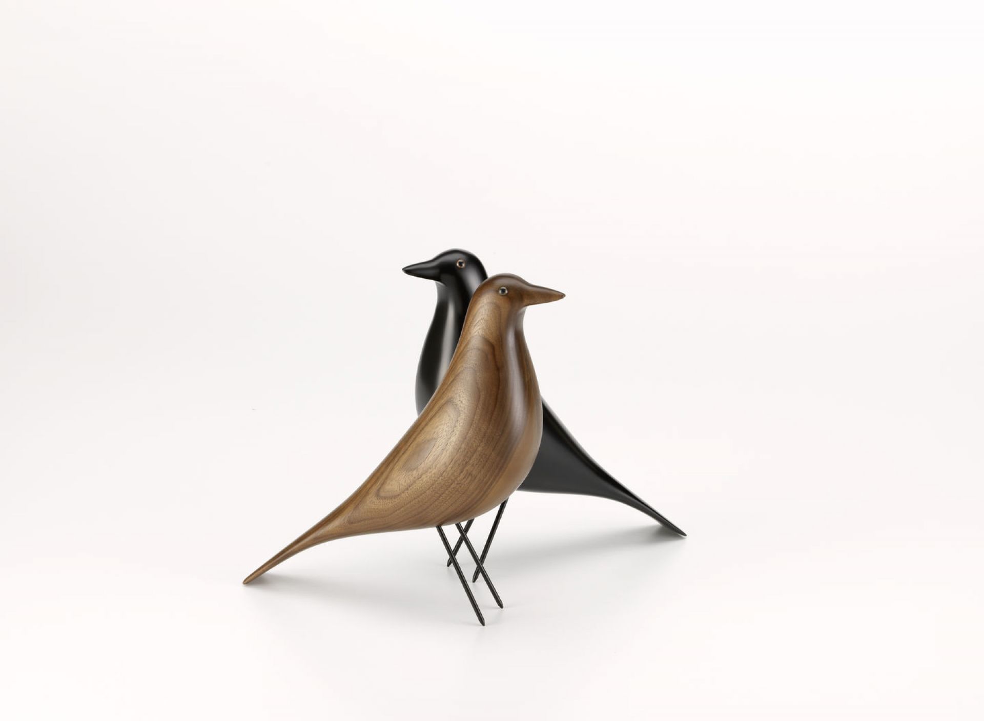 Zwei Eames House Bird Skulpturen von Vitra, eine aus Nussbaum, eine schwarz. Dekorative Designobjekte.