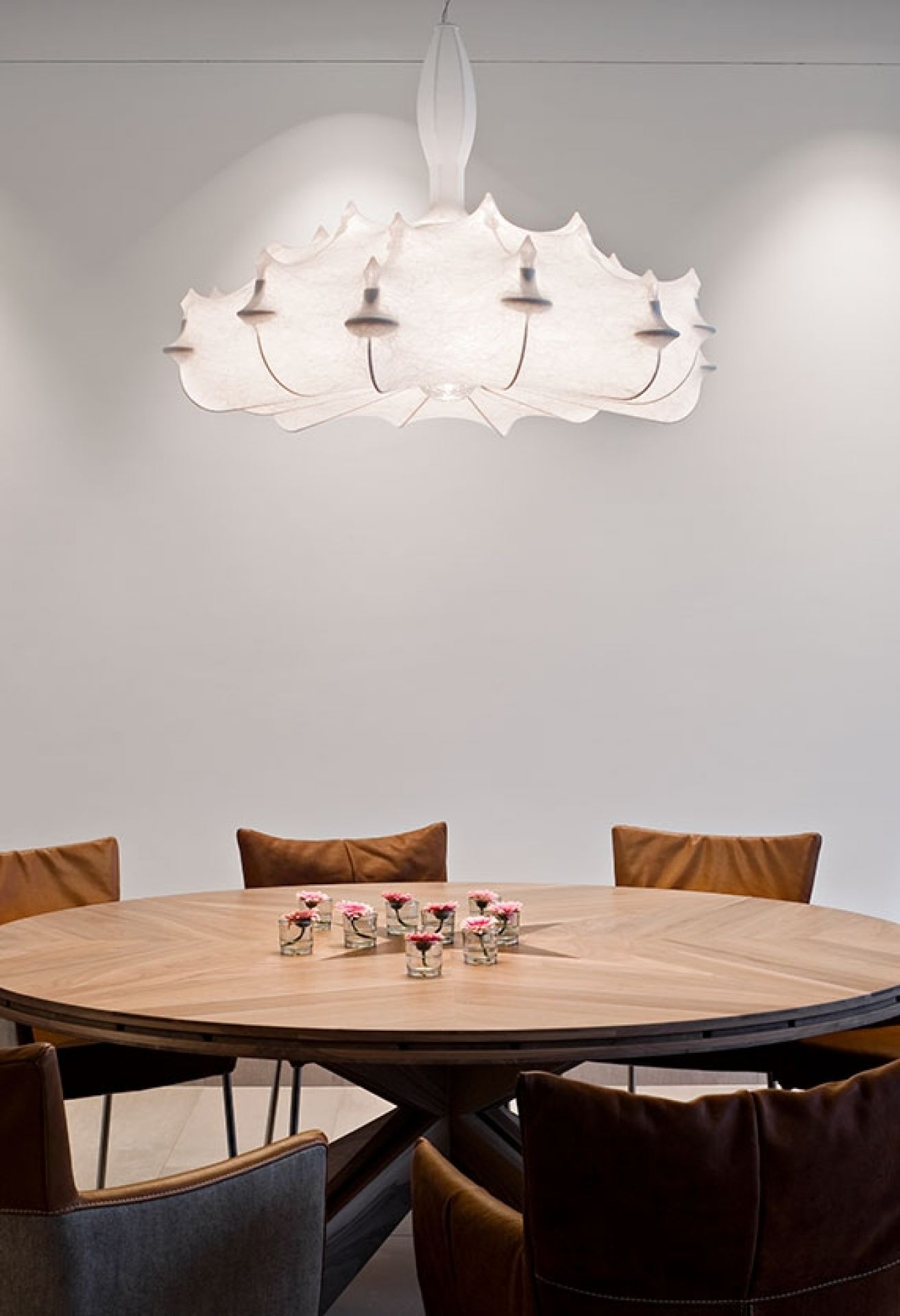 Weiße Flos Zeppelin Hängeleuchte über Esstisch mit Blumen, elegante Innenarchitektur und stimmungsvolle Beleuchtung.