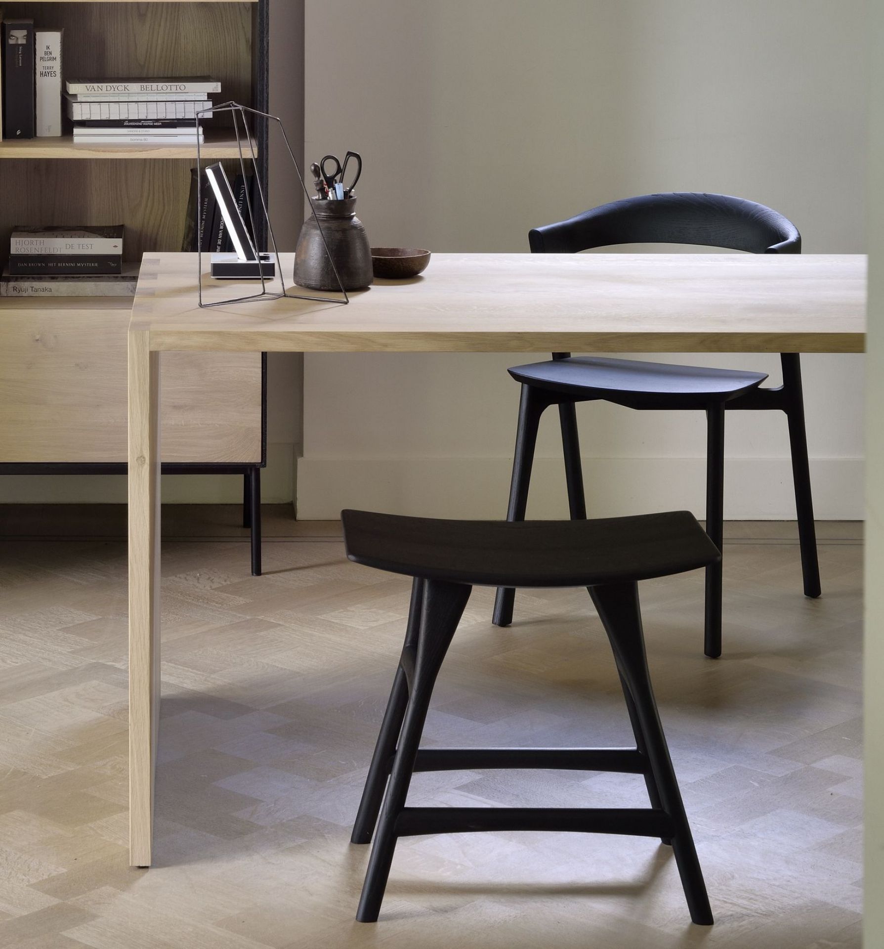 Nahaufnahme von zwei schwarzen Osso Stühlen aus Eiche von Ethnicraft an einem Holztisch.