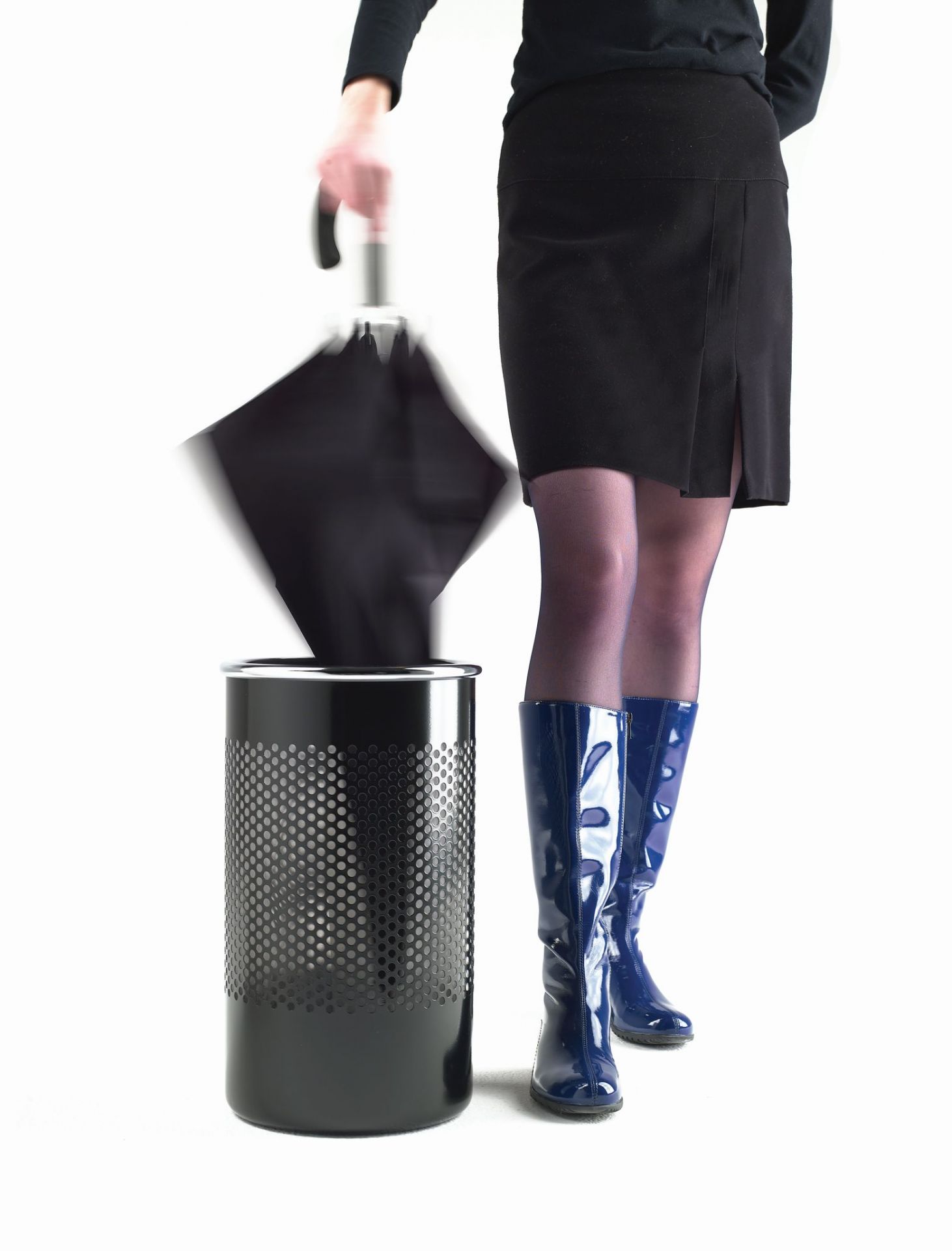 Frau wirft Schirm in Cribbio Schirmständer/Papierkorb. Designobjekt für Büro und Zuhause. Schirmständer aus Metall.