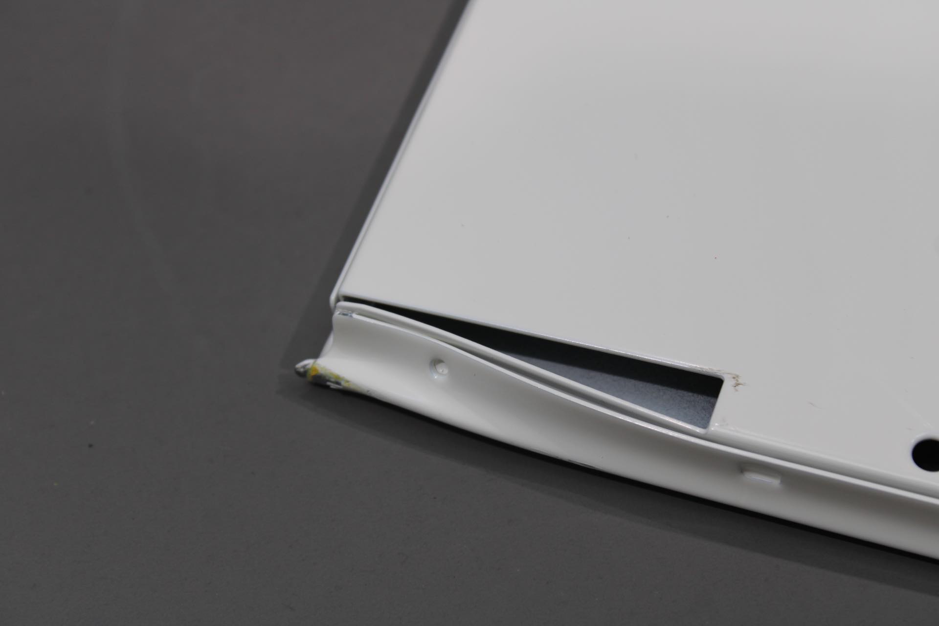 Detailaufnahme einer reinweißen USM Haller Klapptür (Mängelexemplar) mit Beschädigung. Ersatzteil für Möbel.