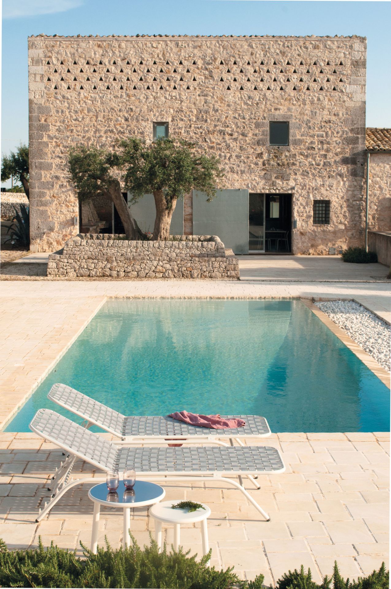 Emu Yard Beistelltisch in Weiß neben Pool und Liegestühlen, ideal für den Garten.