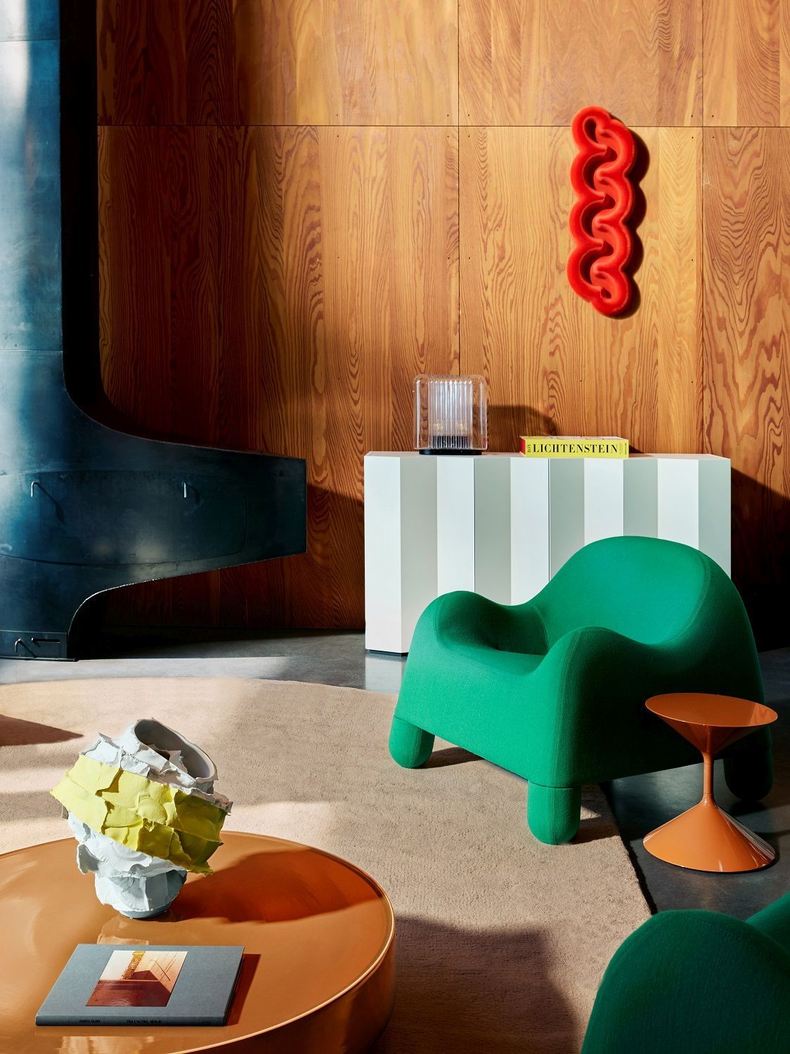 Modernes Wohnzimmer Interieur mit Z24 Sideboard von Zanotta, grüner Sessel und Designobjekten auf beigem Teppich.