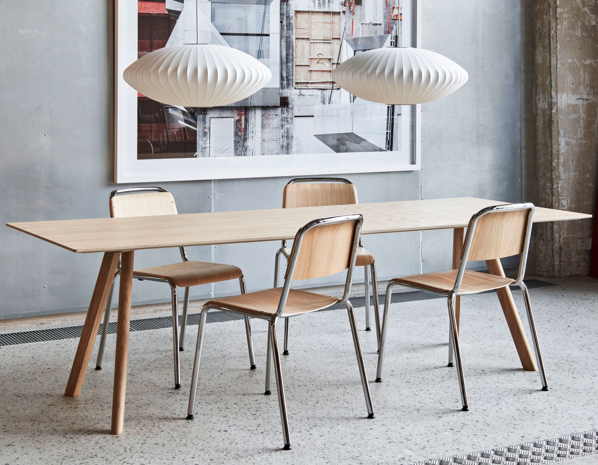 Zwei Nelson Saucer Bubble Pendant Lampen von Hay über einem Esstisch mit Stühlen.