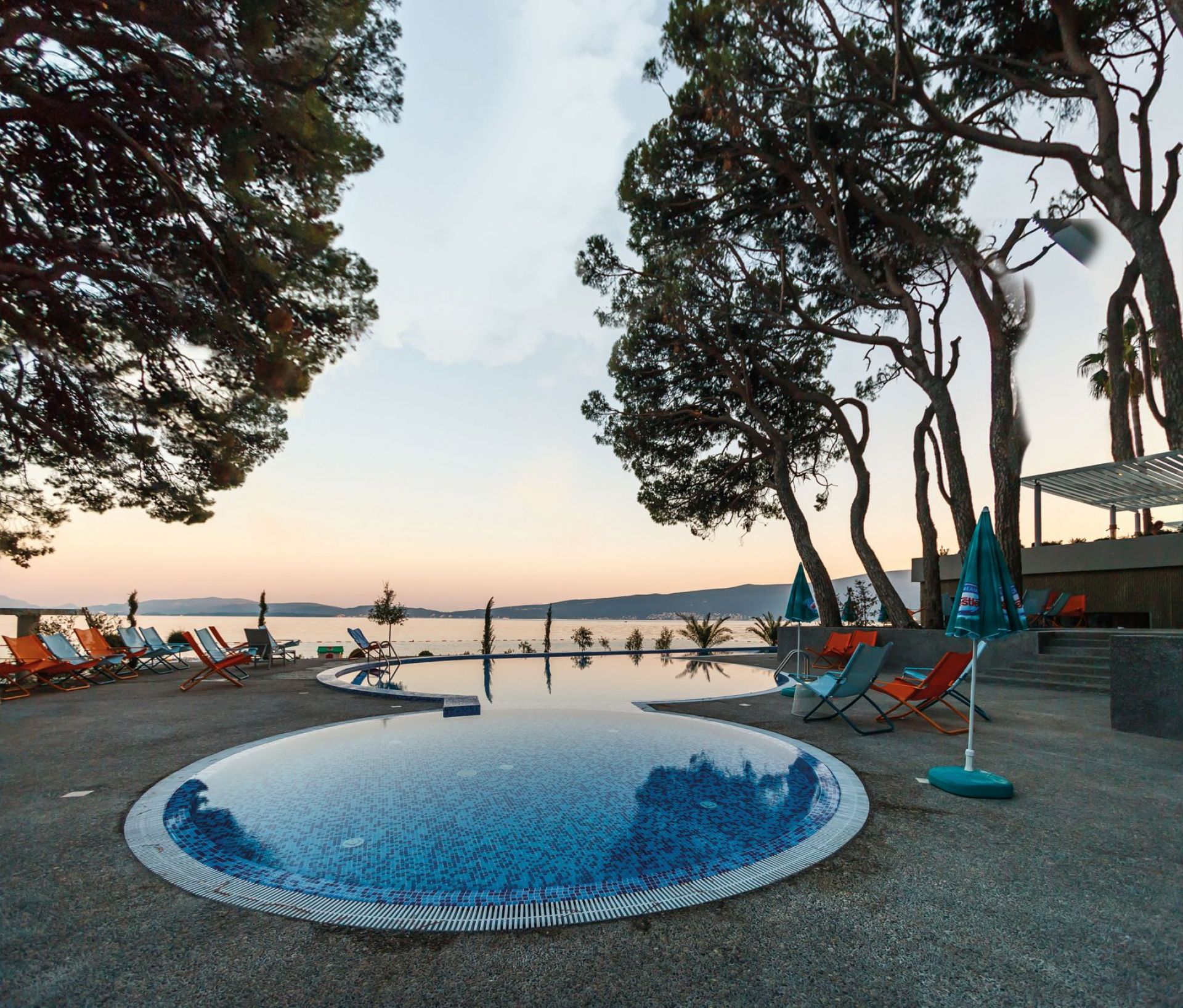 Snooze Liegestuhl Emu: Entspannter Liegestuhl in indianbraun und beige am Pool mit Meerblick.