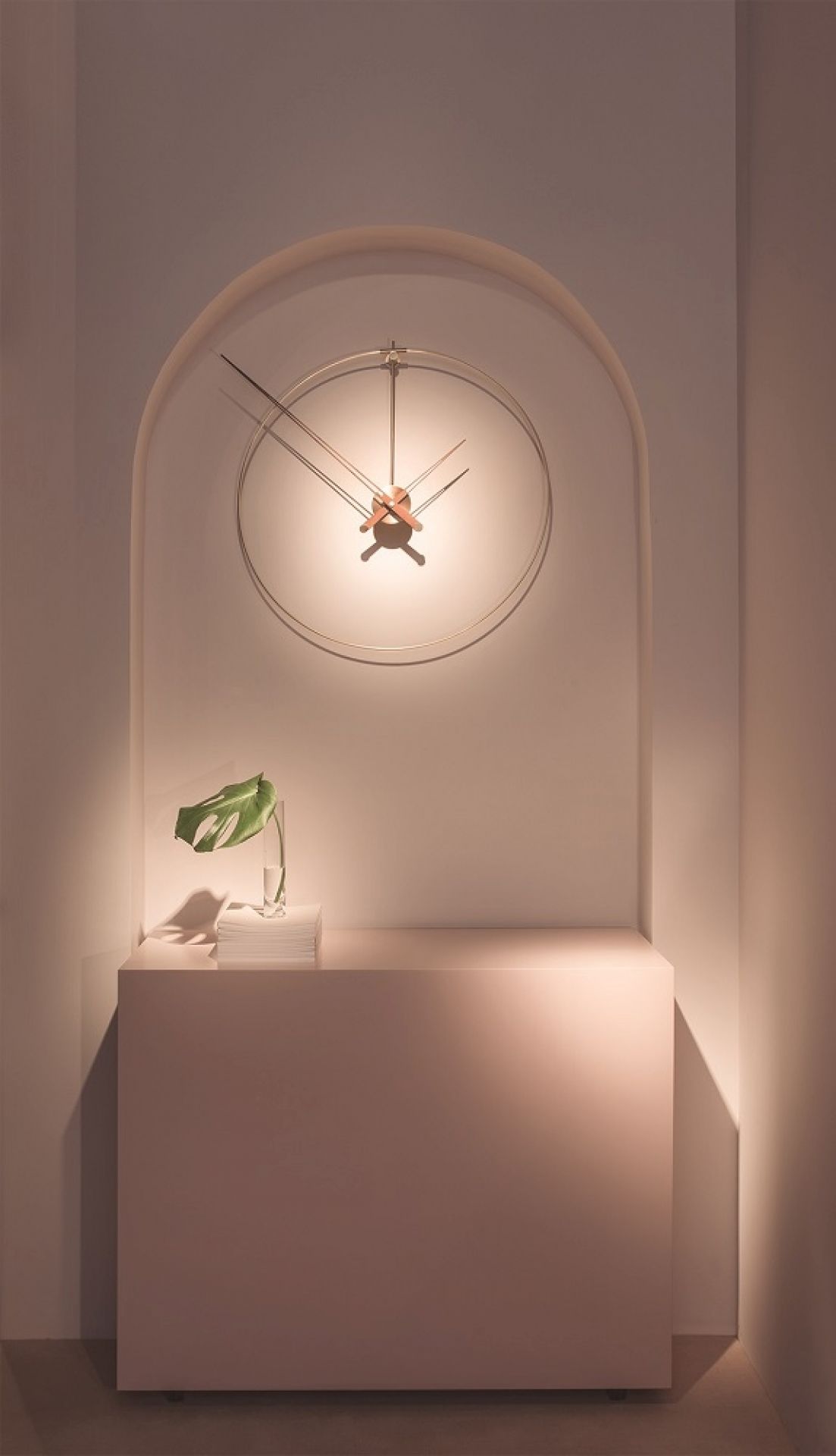 New Anda G Wanduhr: Runde, goldene Designer-Uhr mit minimalistischem Zifferblatt und braunen Zeigern an der Wand.