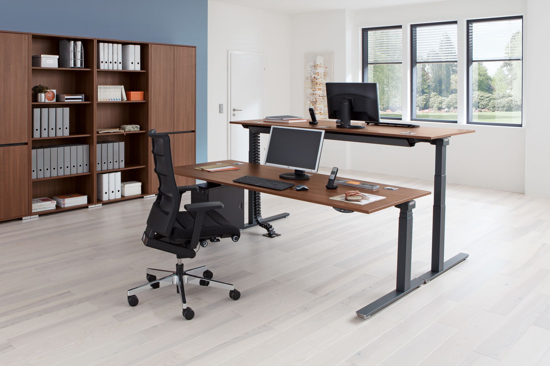 Büro mit Palmberg Schreibtisch, höhenverstellbar, in Holzoptik mit zwei Ebenen und Büromöbeln.