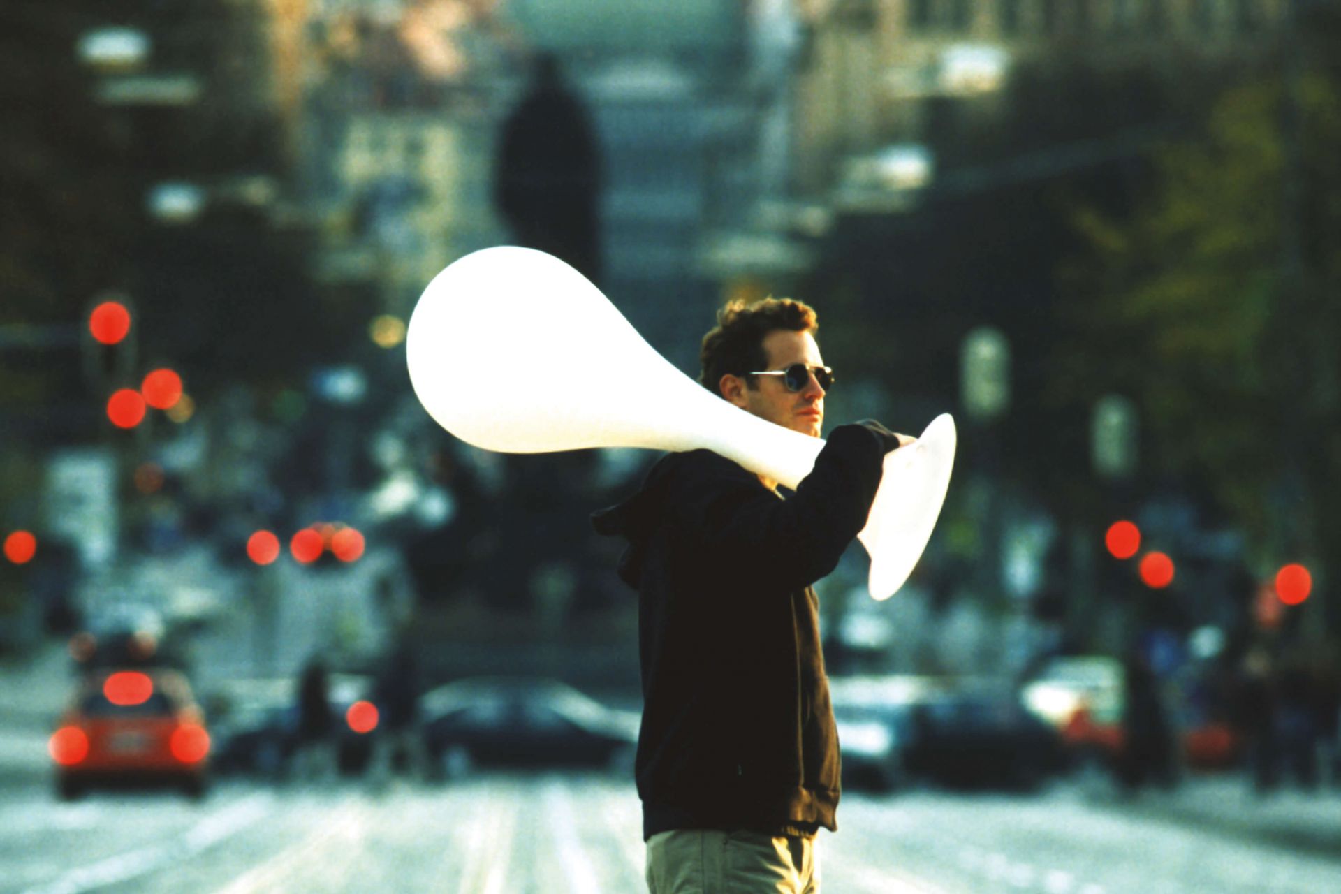 Mann trägt Liquid Light Drop Outdoor Leuchte von Next auf einer belebten Straße.