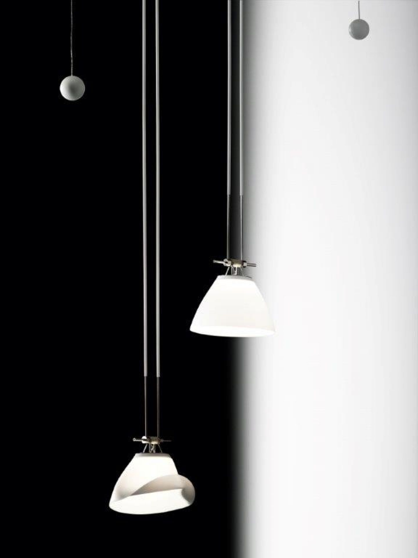 YAYAHO Lichtsystem von Ingo Maurer: Zwei Hängelampen mit weißen Lampenschirmen vor schwarz-weißem Hintergrund.