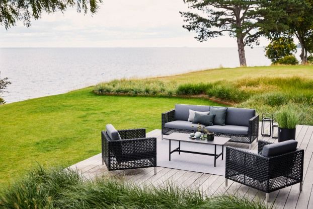 Connect 3-Sitzer Sofa von Cane-Line in Grau mit Sitzpolstern auf einer Terrasse.
