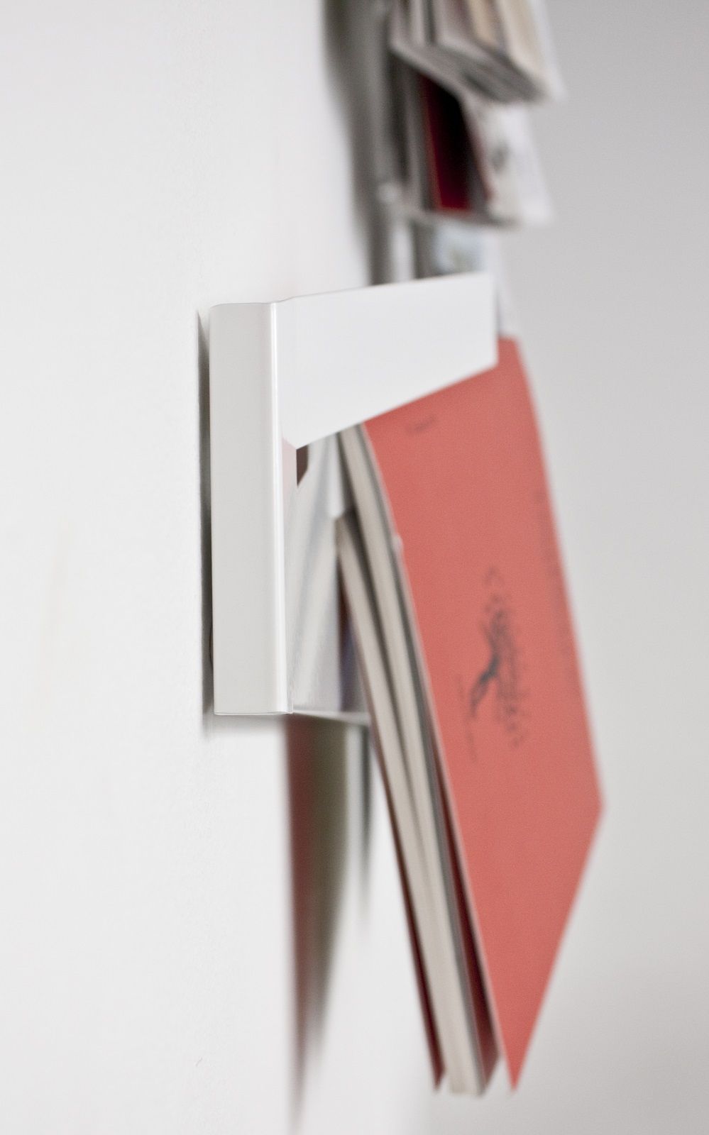 Weißer Mr_Magazinhalter von Müller Möbelwerkstätten an einer Wand mit Zeitschriften. Wandregal für Magazine.