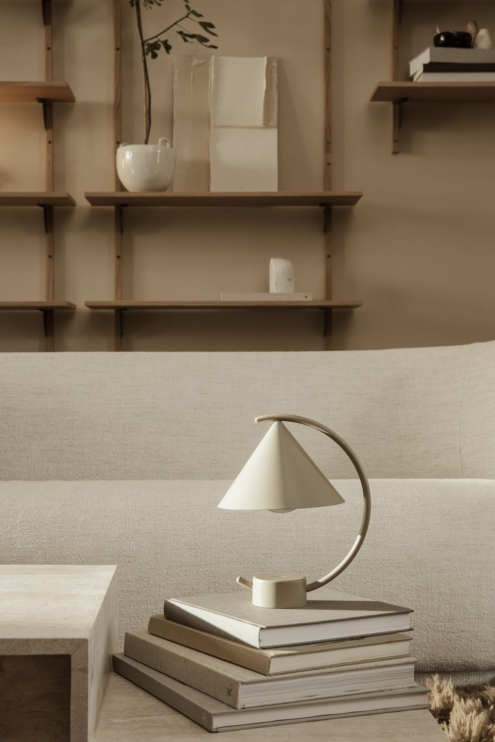 Meridian Lampe von Ferm Living in Cashmere auf einem Bücherstapel, moderne Tischleuchte.