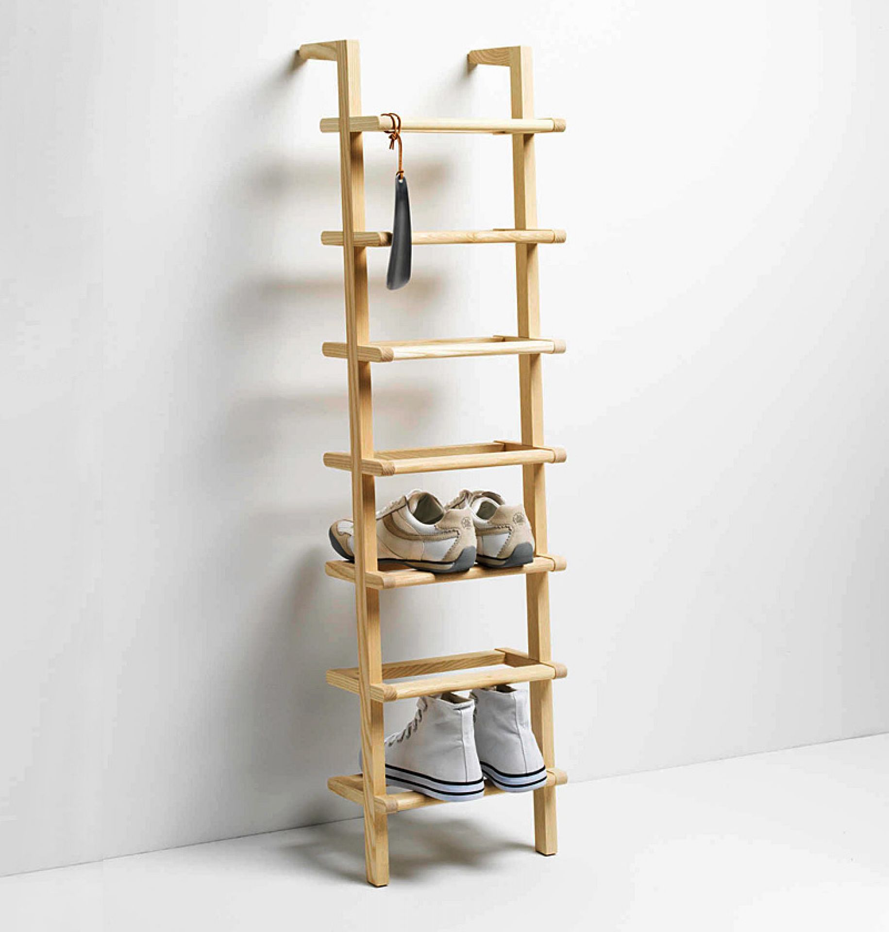 Lady Long Schuhregal aus Holz mit Schuhen und Schuhlöffel an der Wand.