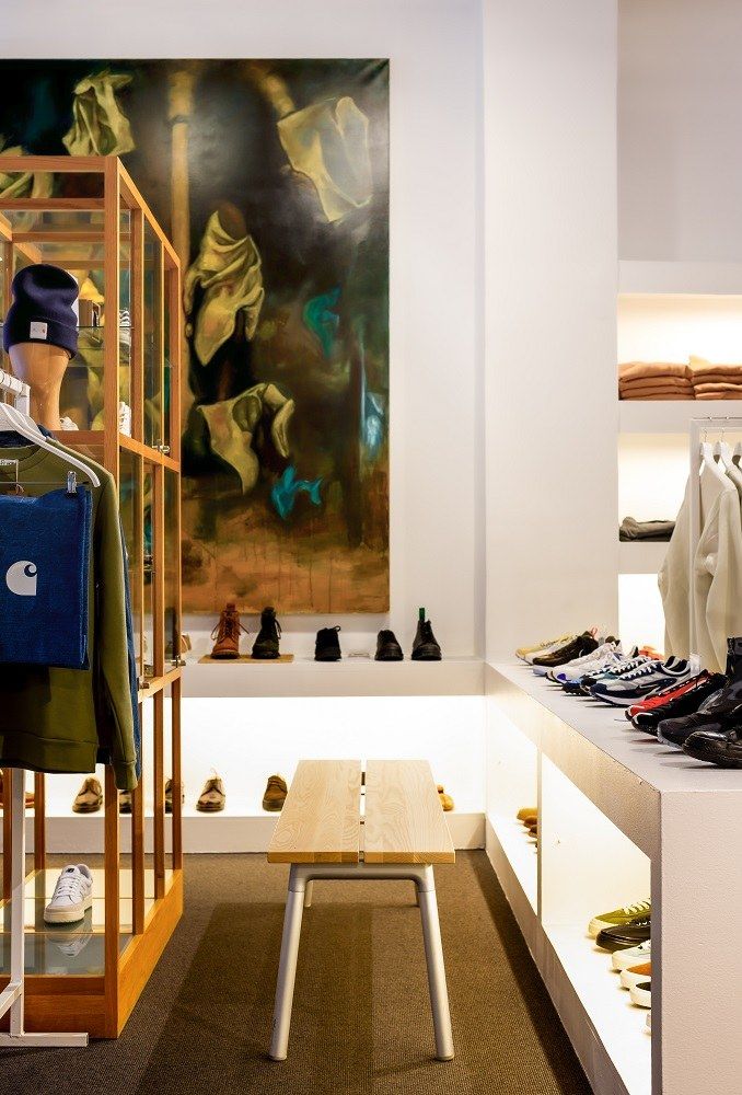 Run Bench Bank mit hellem Holz und silberfarbenem Gestell in einem modernen Schuhgeschäft.