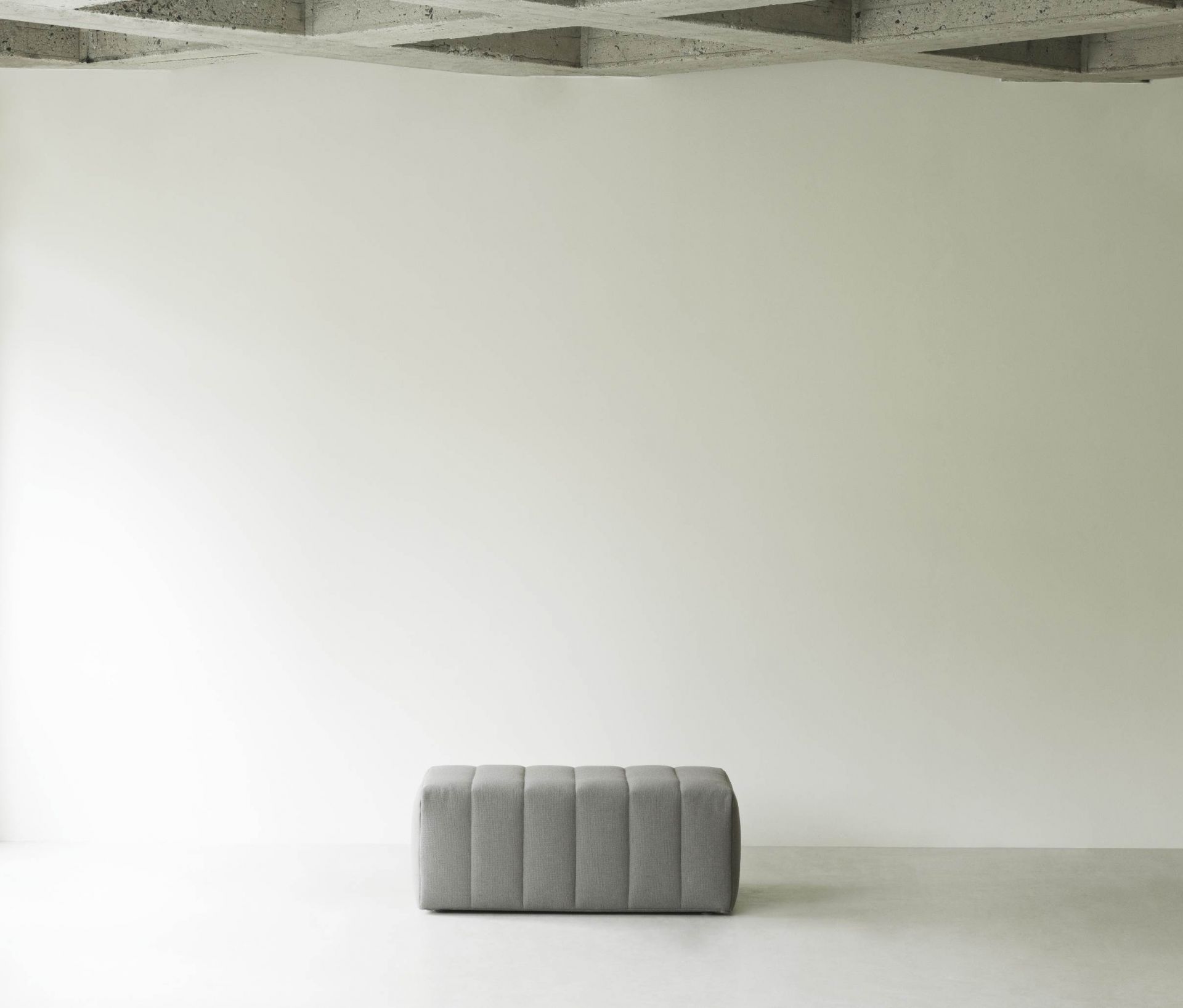 Grauer Scene Pouf Hocker von Normann Copenhagen vor heller Wand. Sitzhocker für Wohnzimmer.