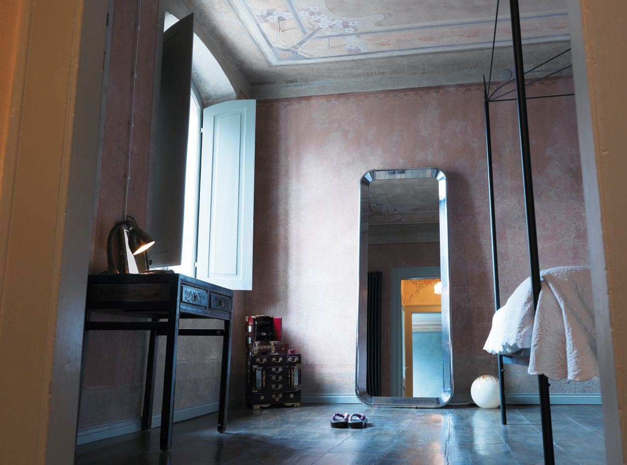 Innenaufnahme mit Magis Deja-vu Spiegel, der in einem Schlafzimmer mit Bett und Schreibtisch steht.