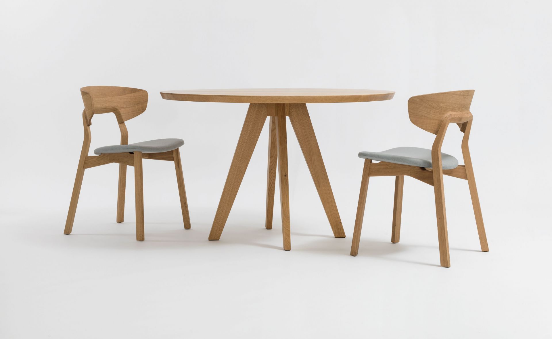 CENA Tisch, runder Esstisch aus Holz mit zwei Stühlen auf weißem Hintergrund.