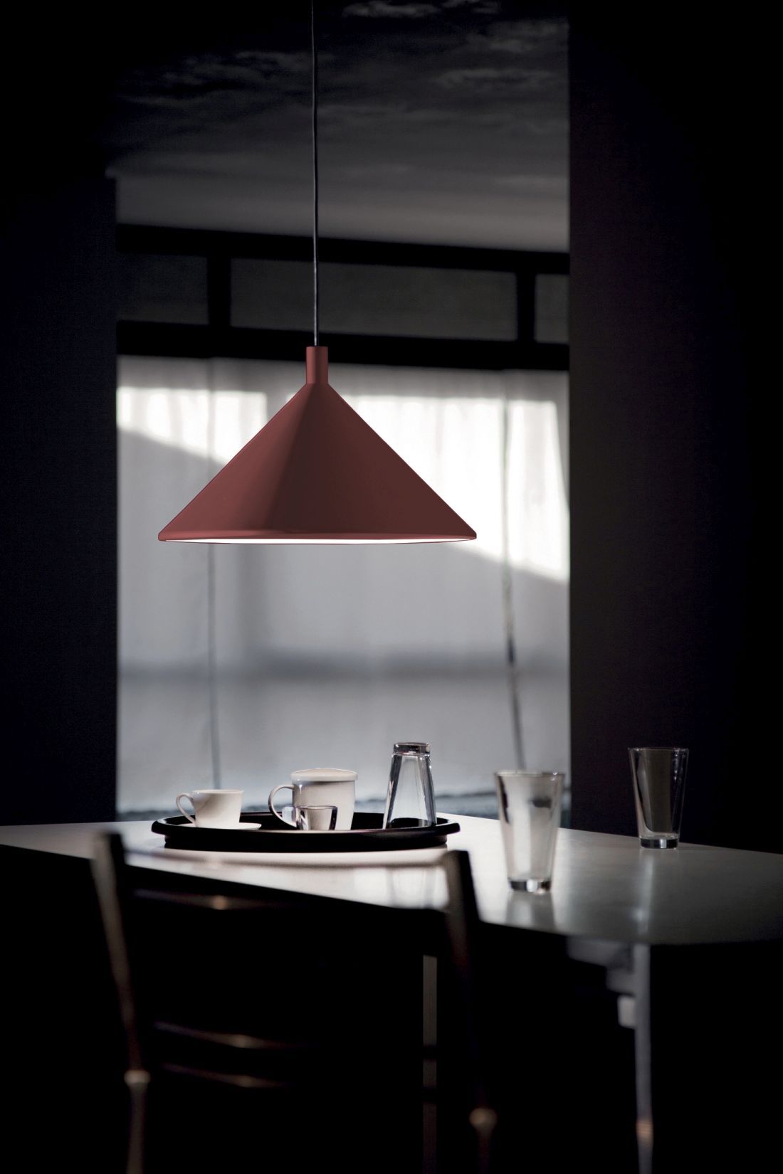 Cono Hängeleuchte von Martinelli Luce in Rot über einem Esstisch mit Geschirr.