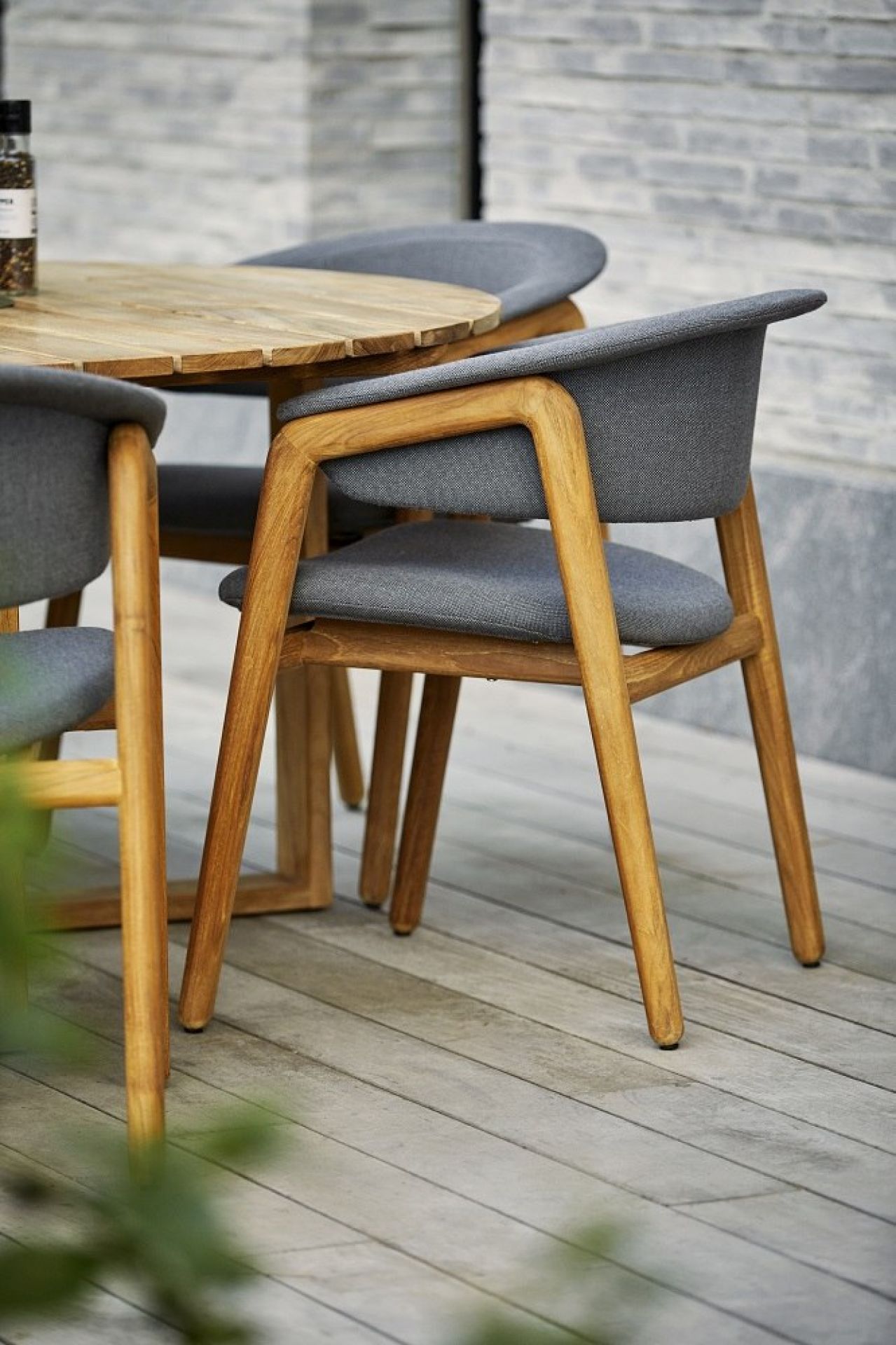 Luna Outdoor Sessel von Cane-Line mit grauem Bezug und Teakholzgestell für den Garten.