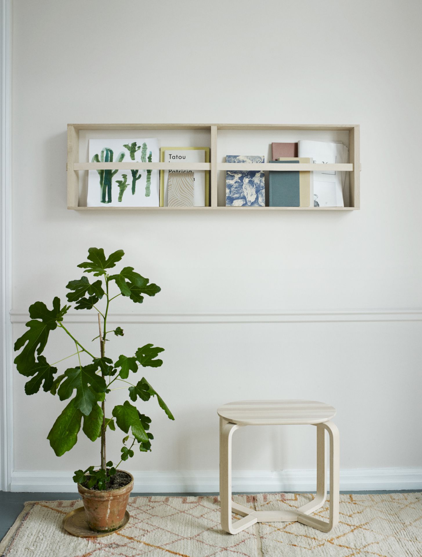 Helles Interieur mit Norr Magazinhalter von Skagerak, gefüllt mit Büchern und Zeitschriften.