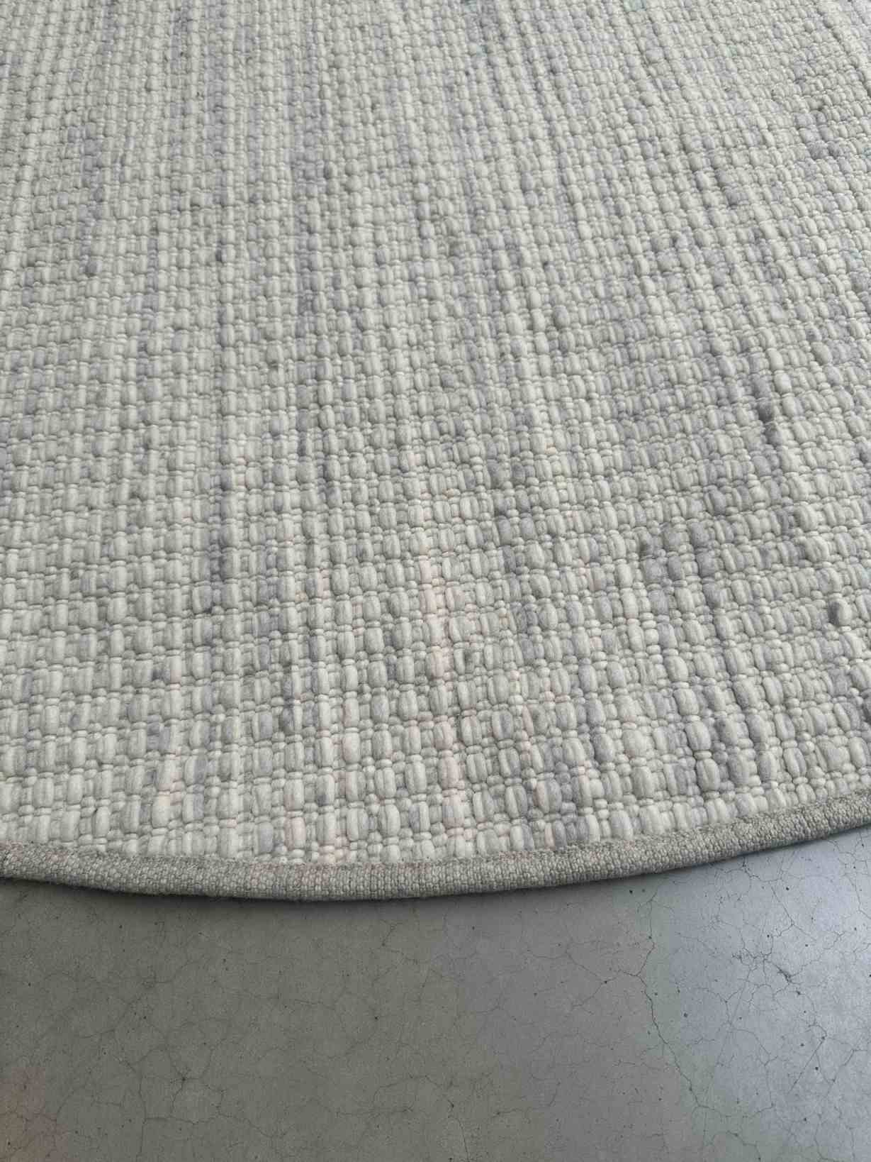 Detailaufnahme des Olbia Mesa Teppichs: Rund, gewebt, weiß und grau, hochwertiger Wollteppich.