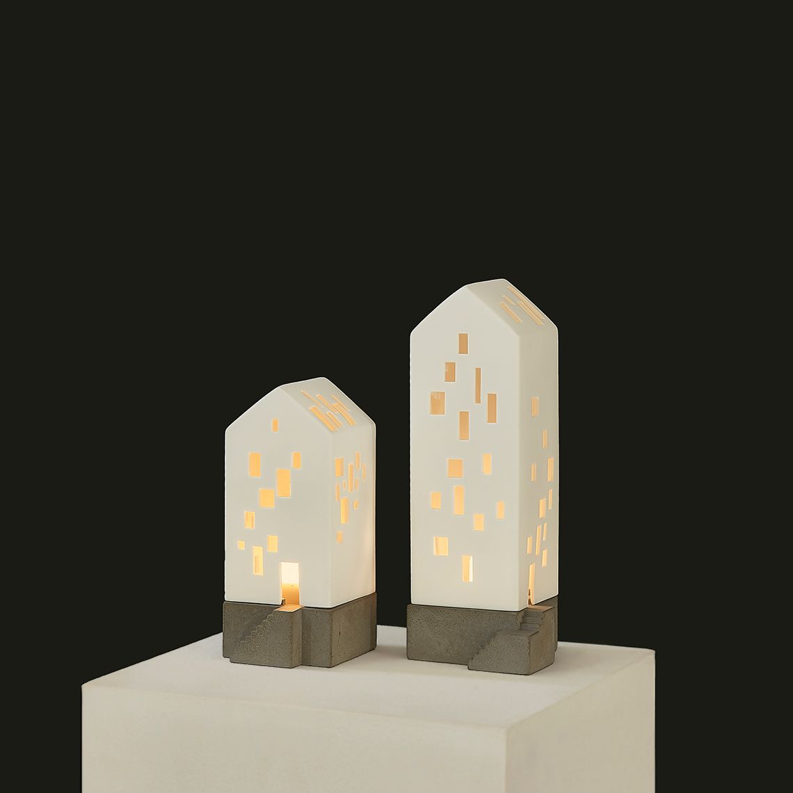 Zwei kleine Apartmenthaus Lichthäuser mit Betonsockel und Rädern, stimmungsvolle Dekoration für Zuhause.