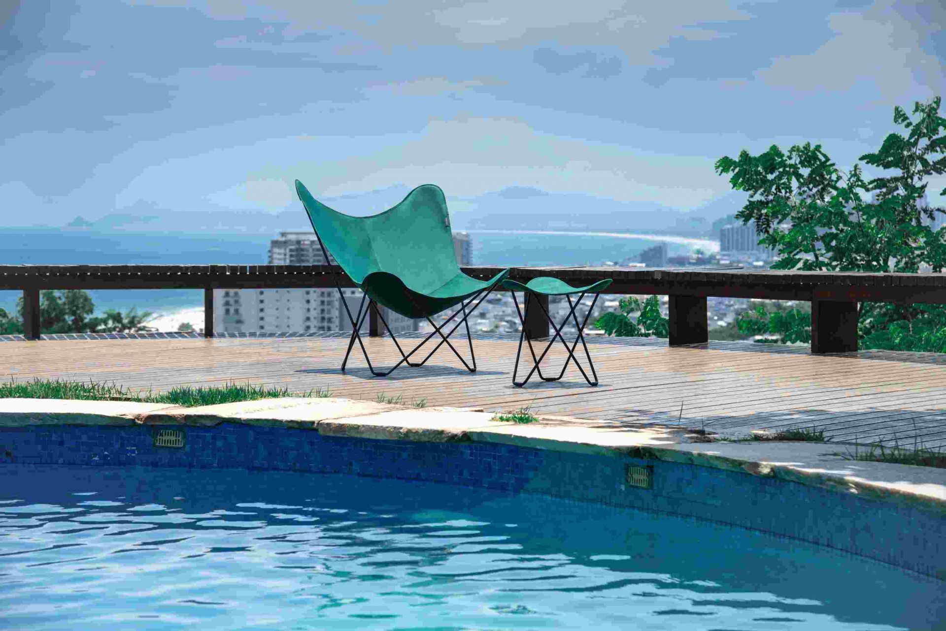 Mariposa Outdoor Butterfly Chair in Waldgrün neben einem Pool auf einer Holzterrasse.