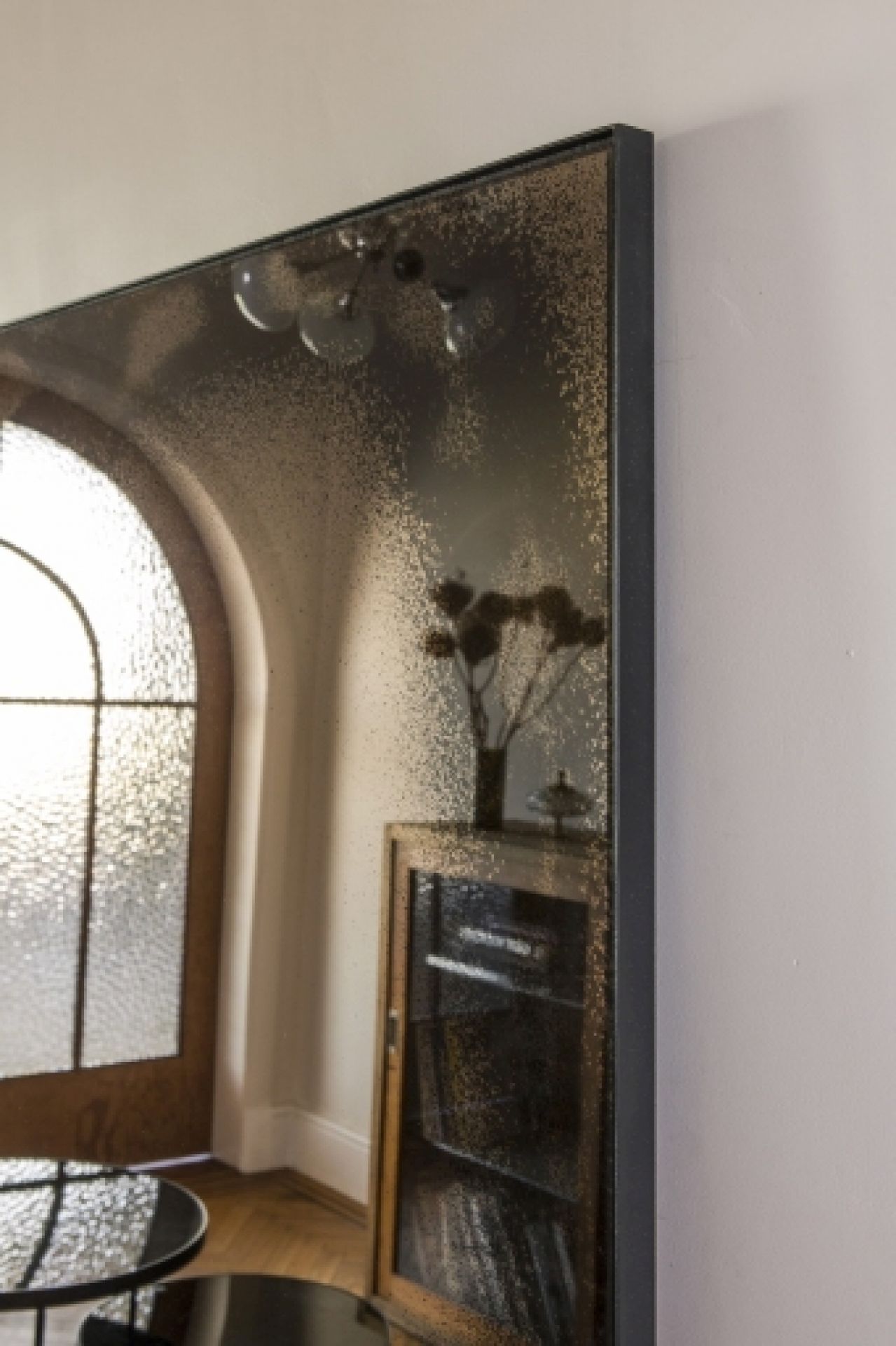 Ethnicraft Wandspiegel im Used-Look mit bronzefarbenem Rahmen, reflektiert stilvolles Interieur und natürliches Licht.