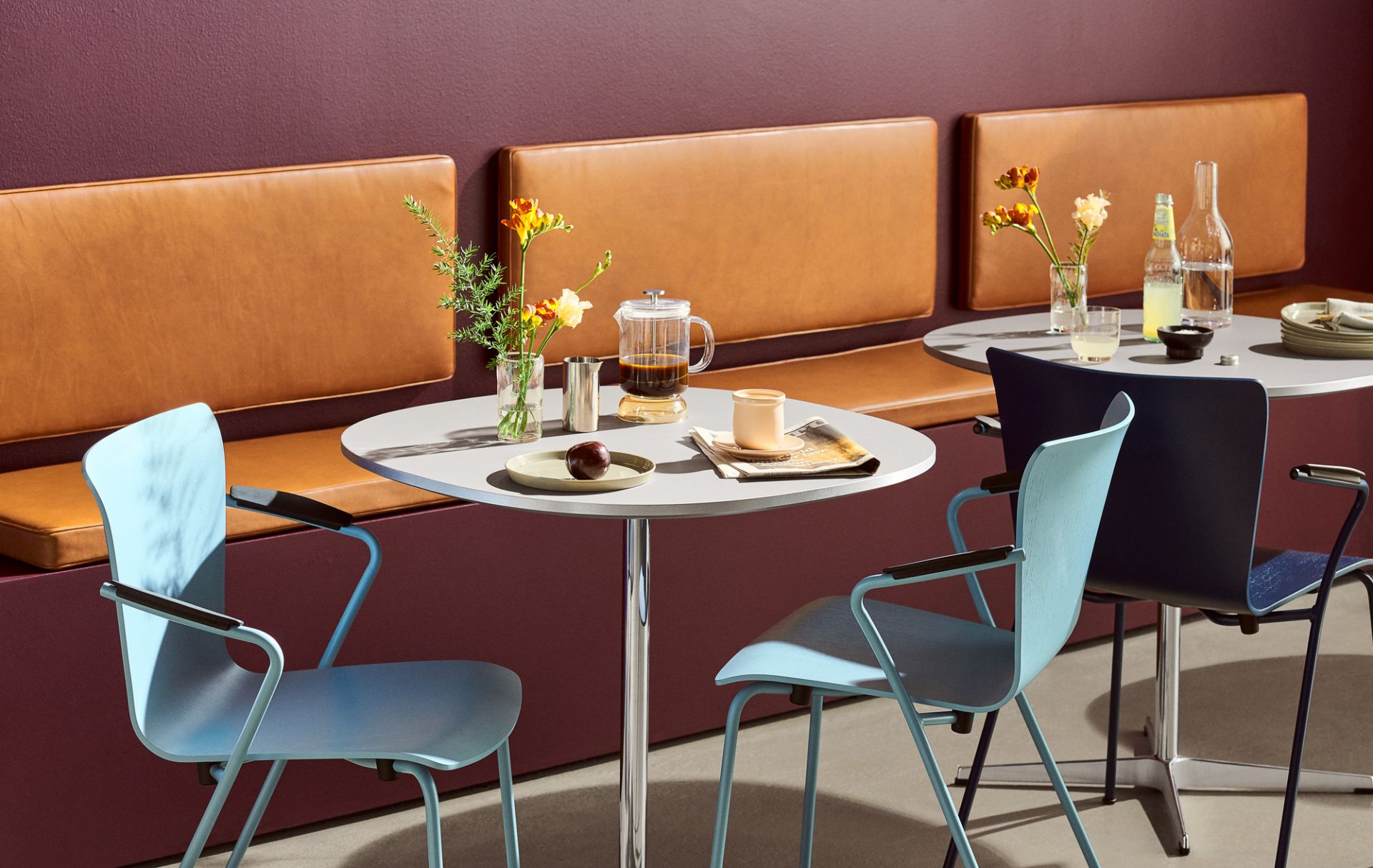 Helle Vico Stühle von Fritz Hansen umgeben Tische in einem modernen Café-Ambiente.