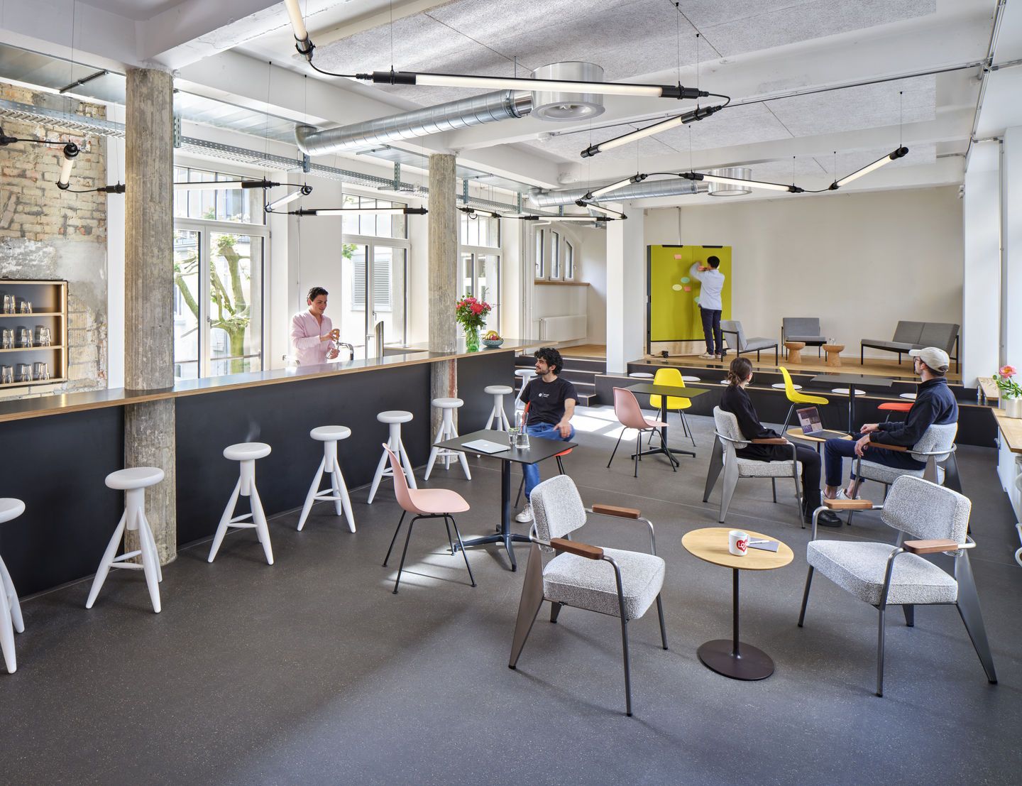 Helles Büro mit mehreren Eames Stühlen, darunter ein vollgepolsterter Vitra DSX Stuhl, für modernes Arbeiten.