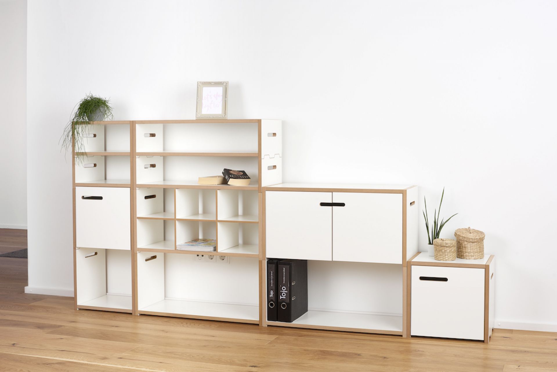 Tojo Halbstark Regalsystem: Weißes, modulares Holzregal mit Fächern, Schubladen und Ablageflächen für Wohnzimmer oder Büro.