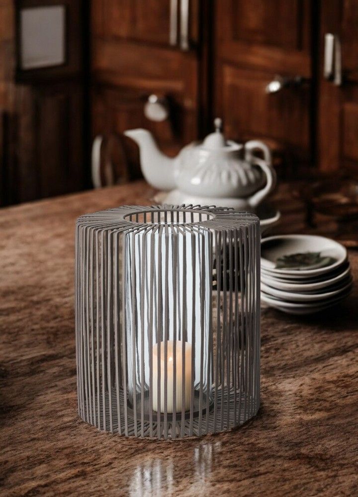 Oslo Windlicht von Philippi, hoch, aus Metall mit Glaszylinder und brennender Kerze.