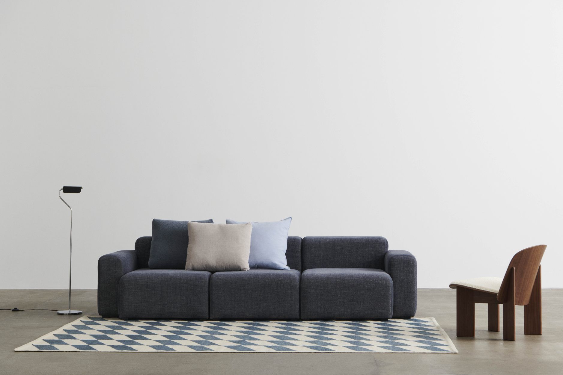 Mags Sofa 3-Sitzer in blauem Linara Stoff mit Kissen und Teppich im minimalistischen Wohnzimmer.