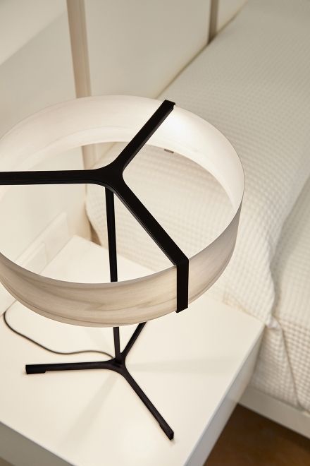 Thesis Tischleuchte von LZF Lamps mit rundem Lampenschirm und schwarzem Gestell auf Nachttisch.