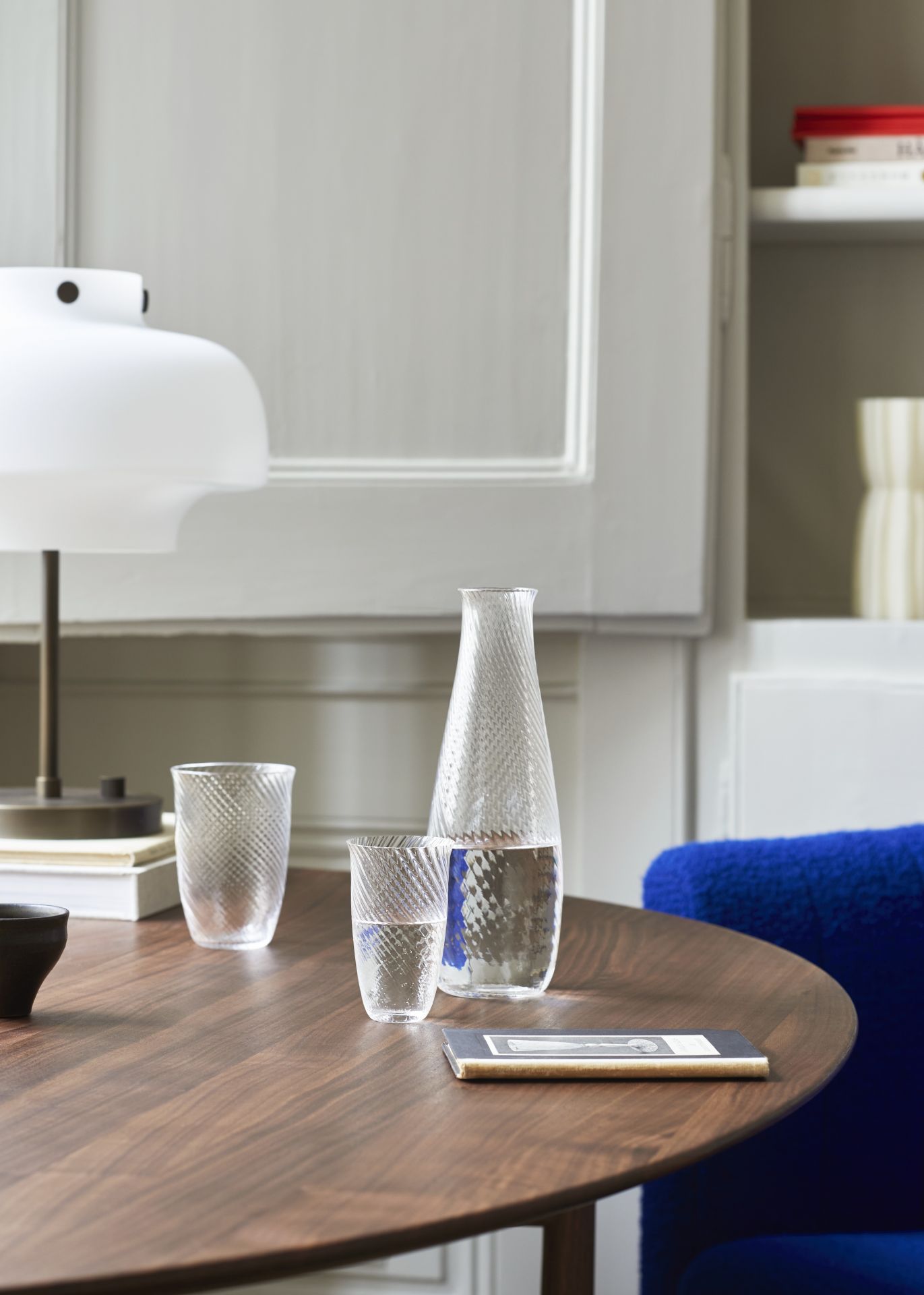 AndTradition Karaffe SC62-SC63 aus Glas mit zwei passenden Gläsern auf einem Holztisch.