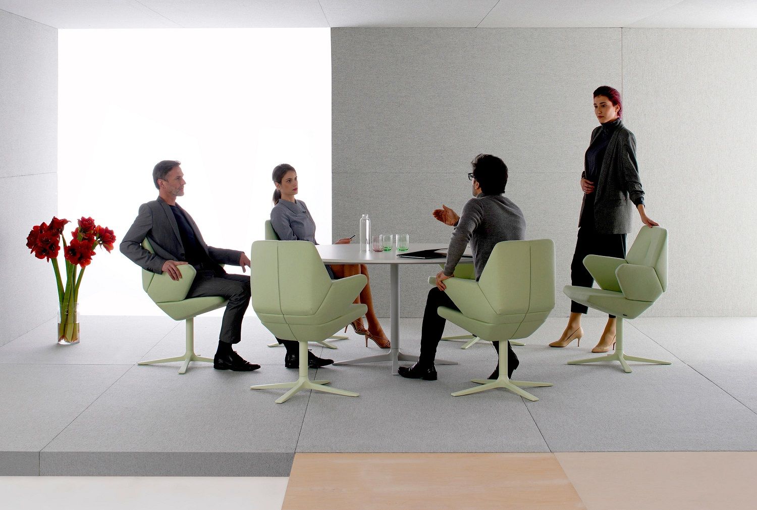 Besprechungsszene mit vier Personen auf hellgrünen Trifidae Konferenzstühlen von Prostoria an einem weißen Tisch.