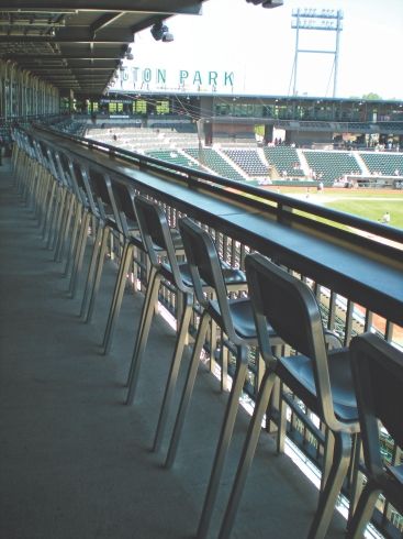 Reihe von Metallstühlen auf einer Tribüne mit Blick auf ein Baseballfeld im Stadion.