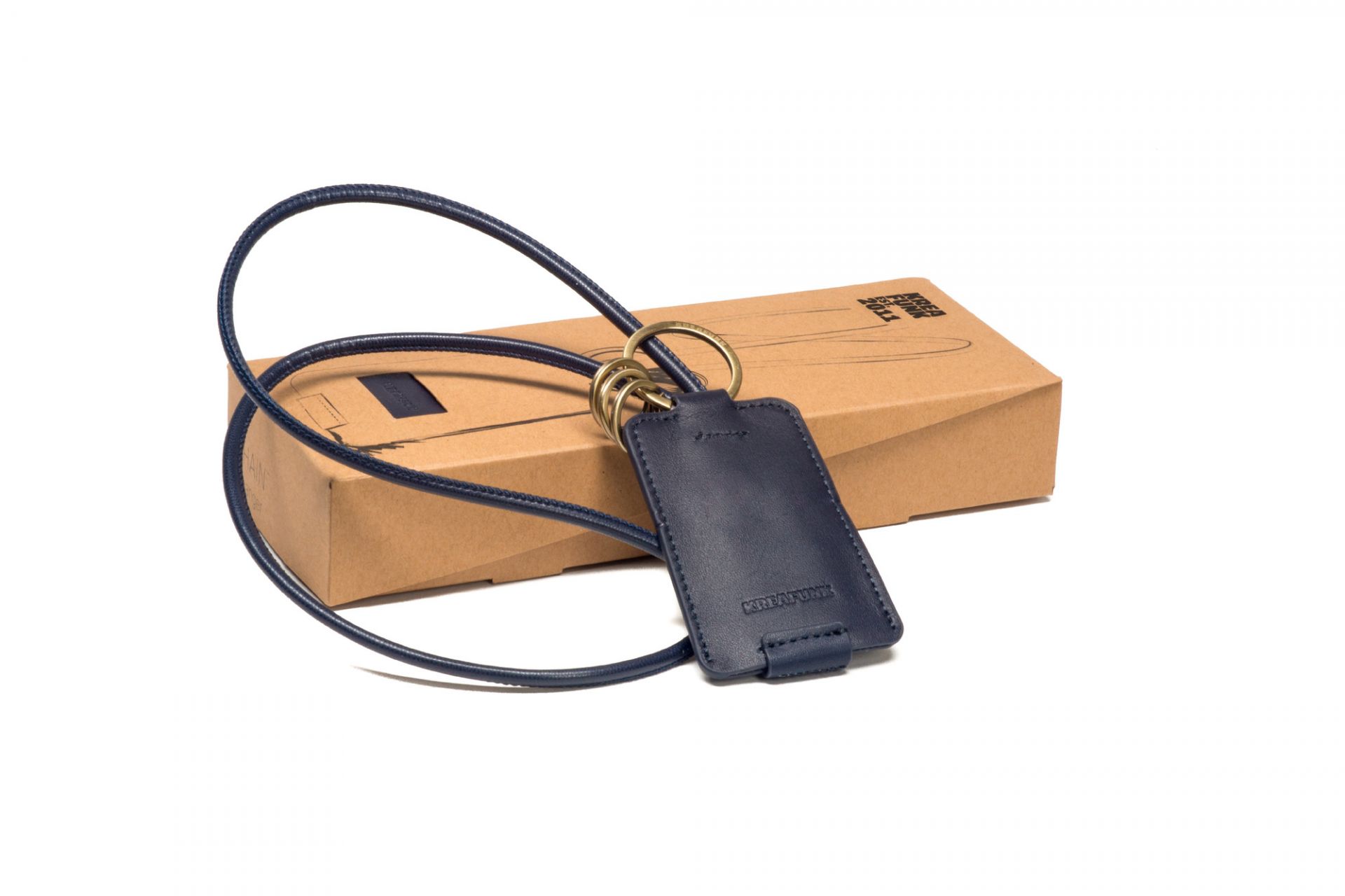 Blauer cCHAIN Schlüsselanhänger von Kreafunk mit USB-Kabel und goldfarbenen Ringen vor einer braunen Verpackung.