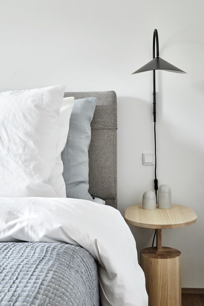 Schlafzimmer-Szene mit Arum Wandleuchte von Ferm Living in Schwarz über Nachttisch. Moderne Wandlampe.