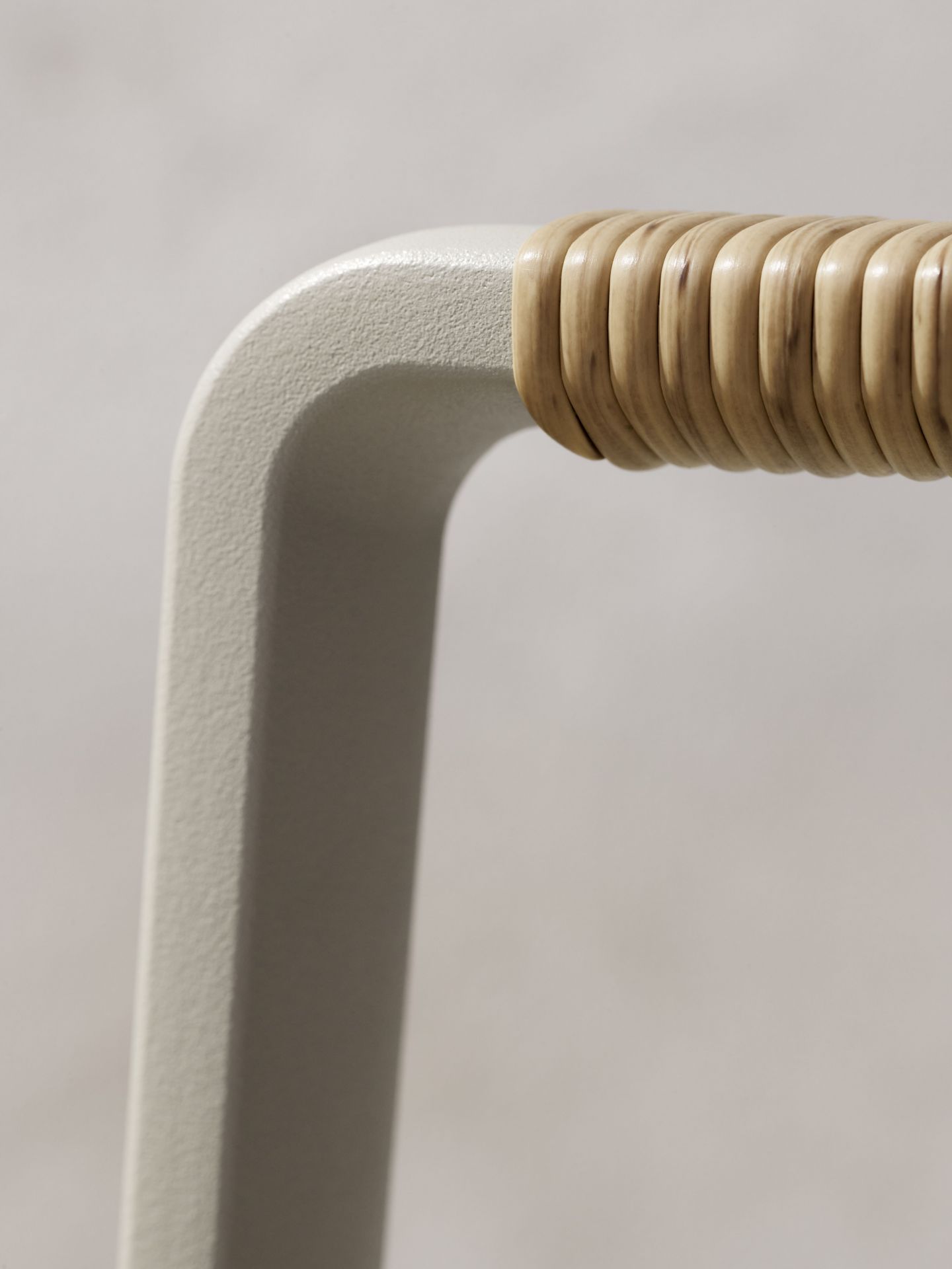 Detailaufnahme des Vipp Open-Air Outdoor Stuhls mit Rattan-Akzenten am pulverbeschichteten Aluminiumrahmen.