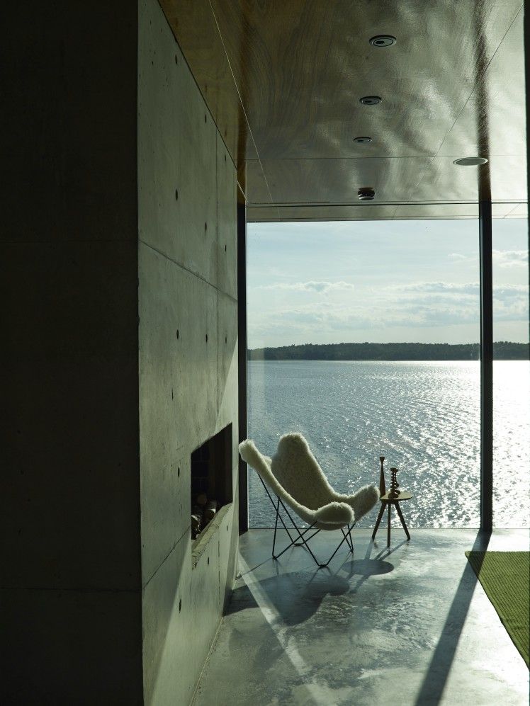 Iceland Mariposa Butterfly Sessel mit Schaffell in Grau vor einem Fenster mit Seeblick.