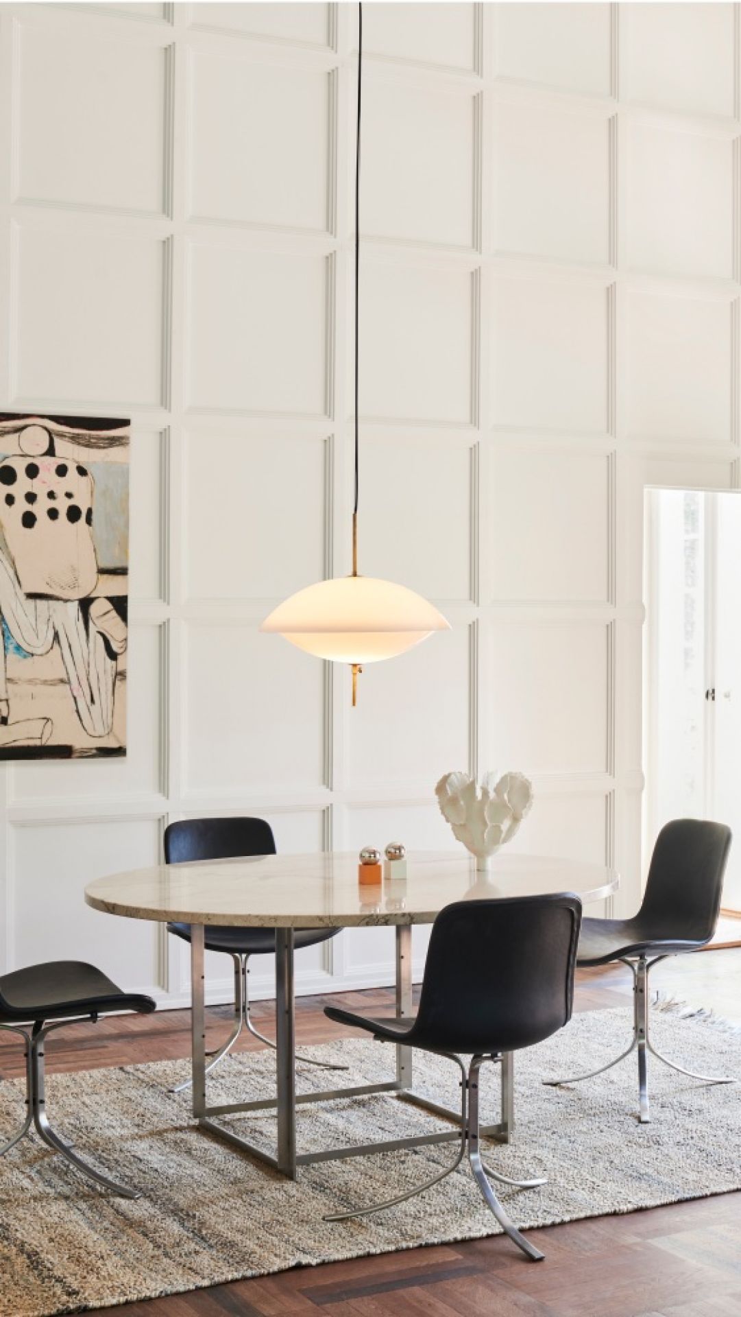 Helle Clam Pendelleuchte von Fritz Hansen über Esstisch mit Stühlen und Teppich.