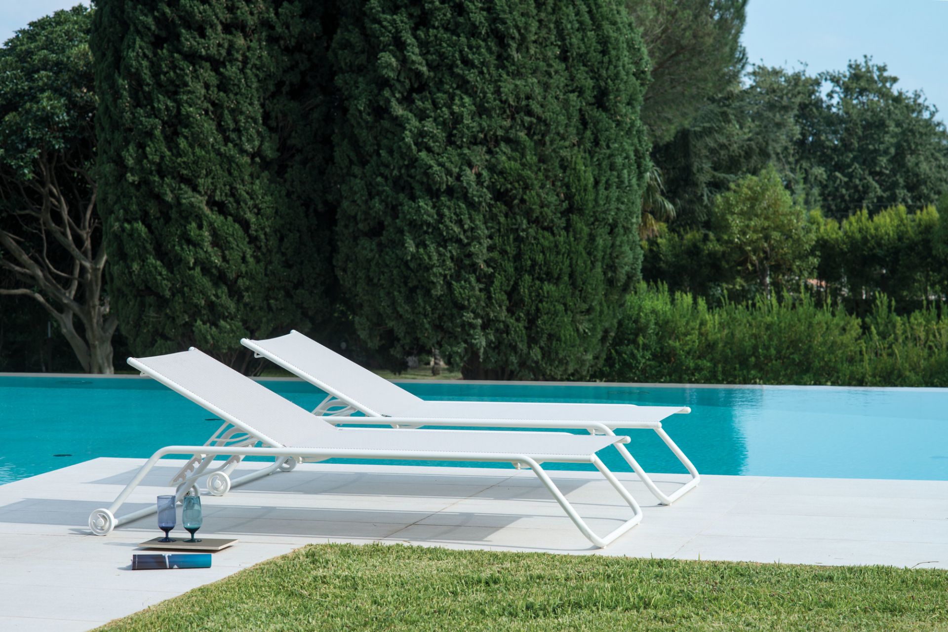 Zwei weiße Emu Snooze Sonnenliegen am Pool, moderne Gartenmöbel für entspannte Sommertage.