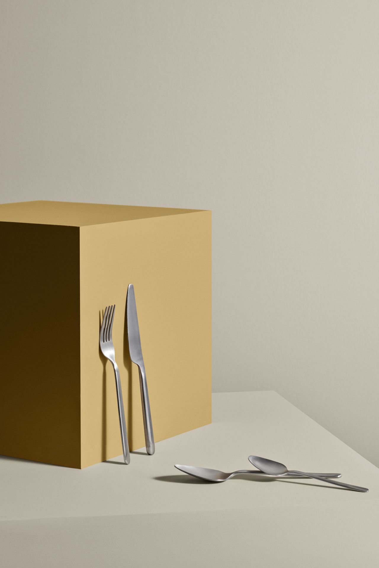 Edelstahl Besteck-Set Stella von Blomus: Messer, Gabel und Löffel auf beigem Untergrund. Modernes Design.